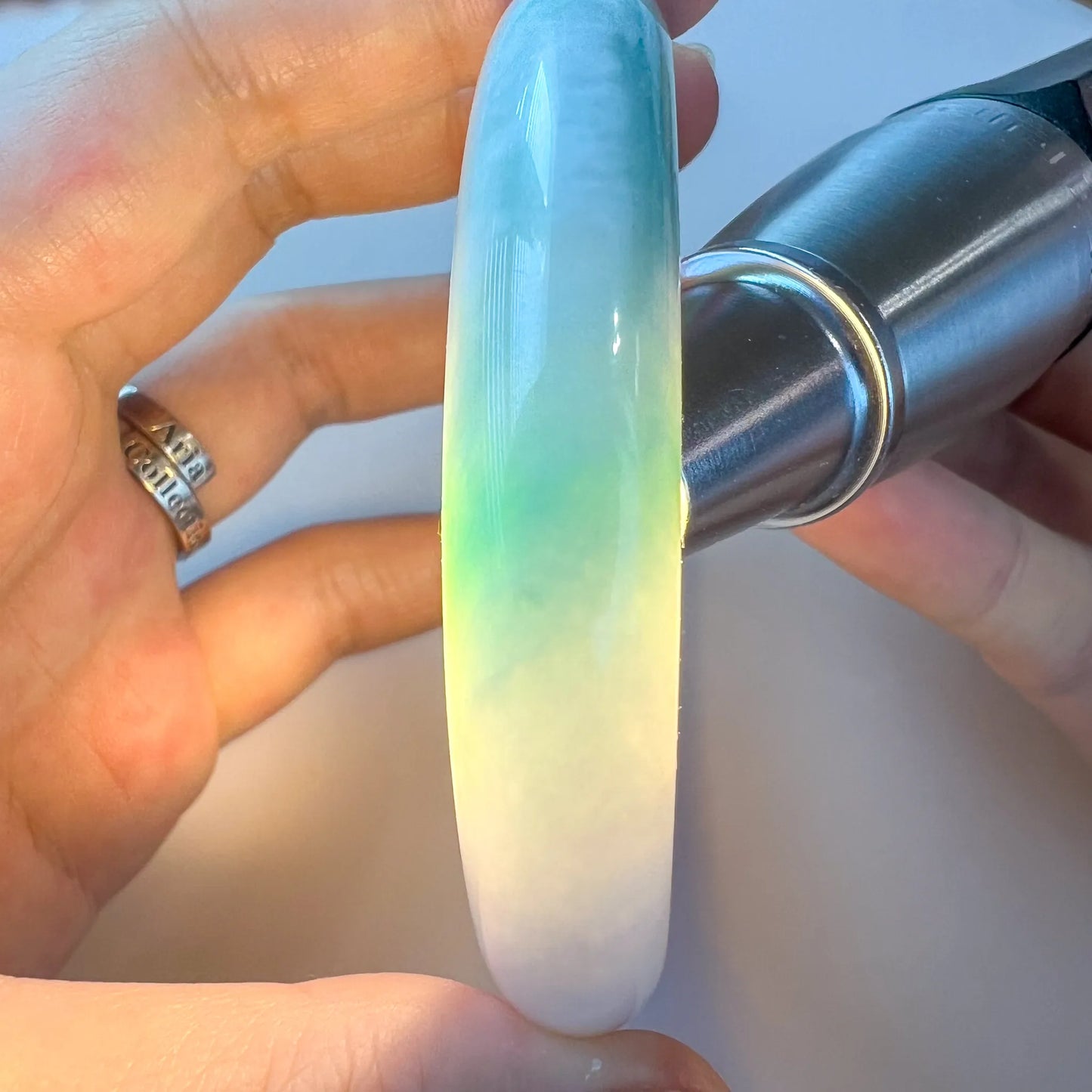 Backlit side view of translucent jade bangle with bright green glow