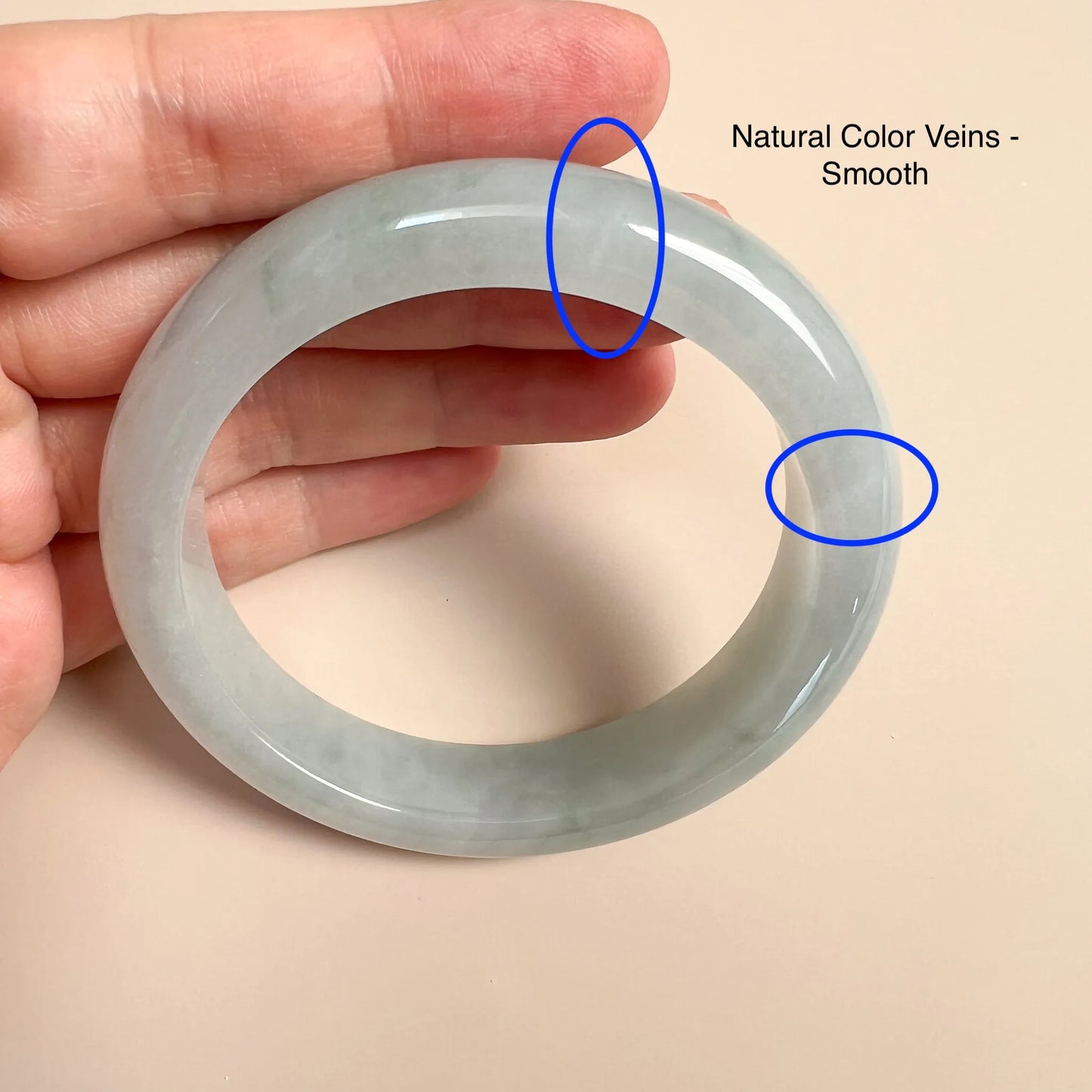 Close-up of jade bangle with natural color veining and glossy polished finish in hand