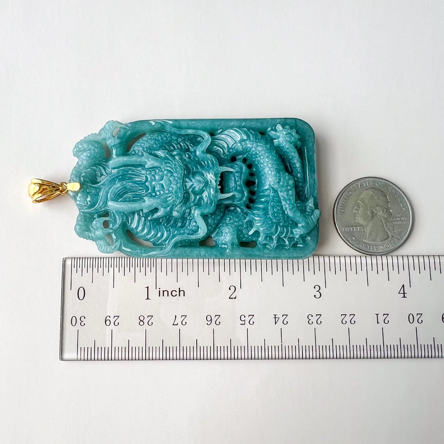 Top-down size comparison of carved dragon pendant with ruler and quarter