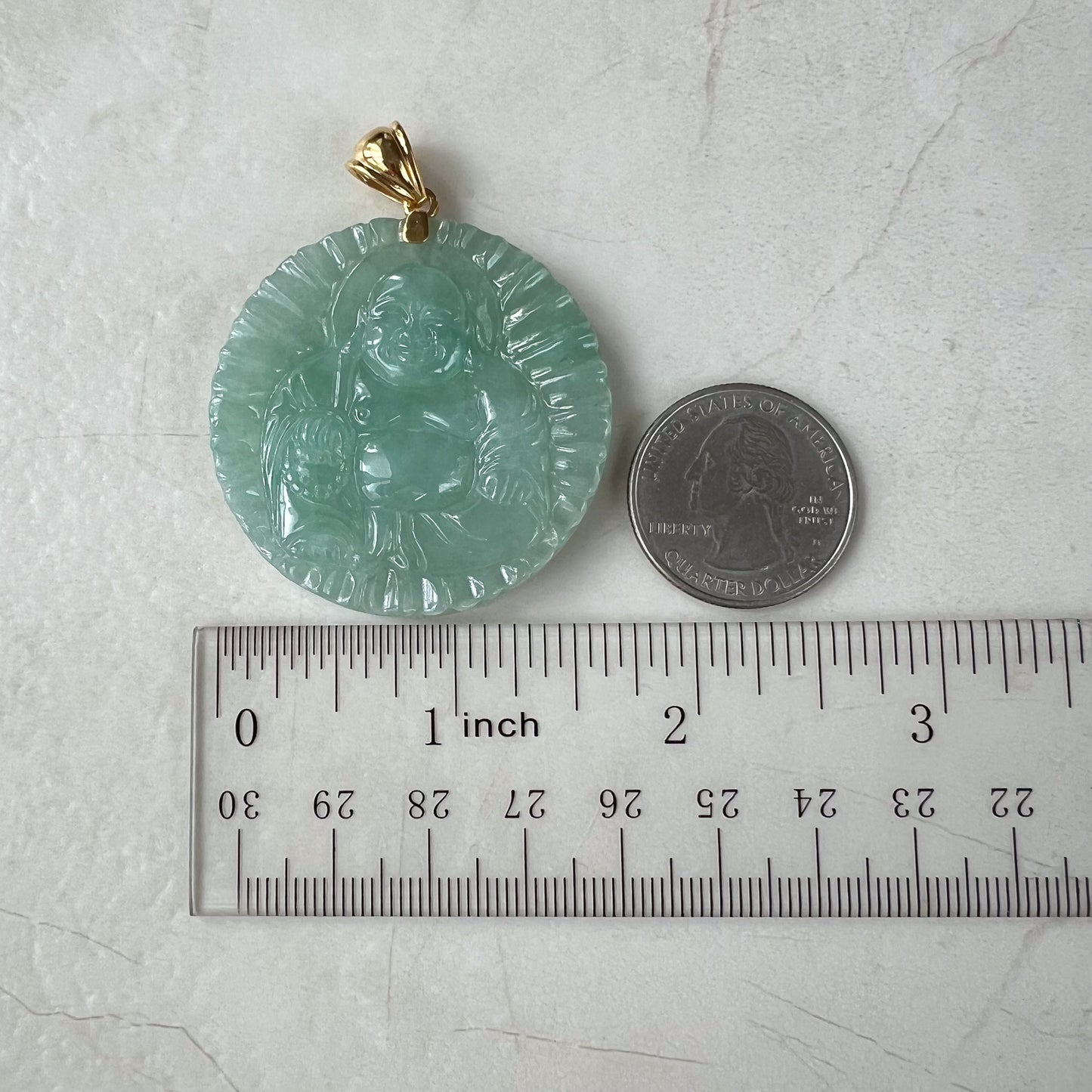 Green jadeite Buddha pendant with 18K gold bail, carved glossy finish, shown beside ruler and quarter for scale