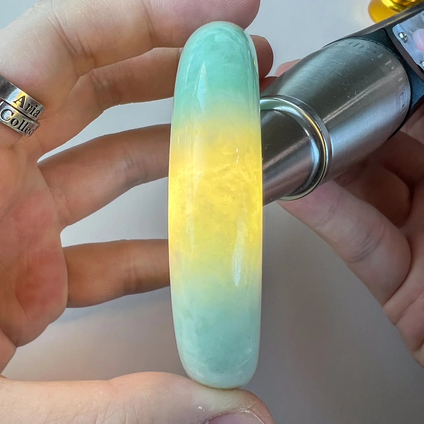 Handheld side view of translucent green and yellow jade bangle