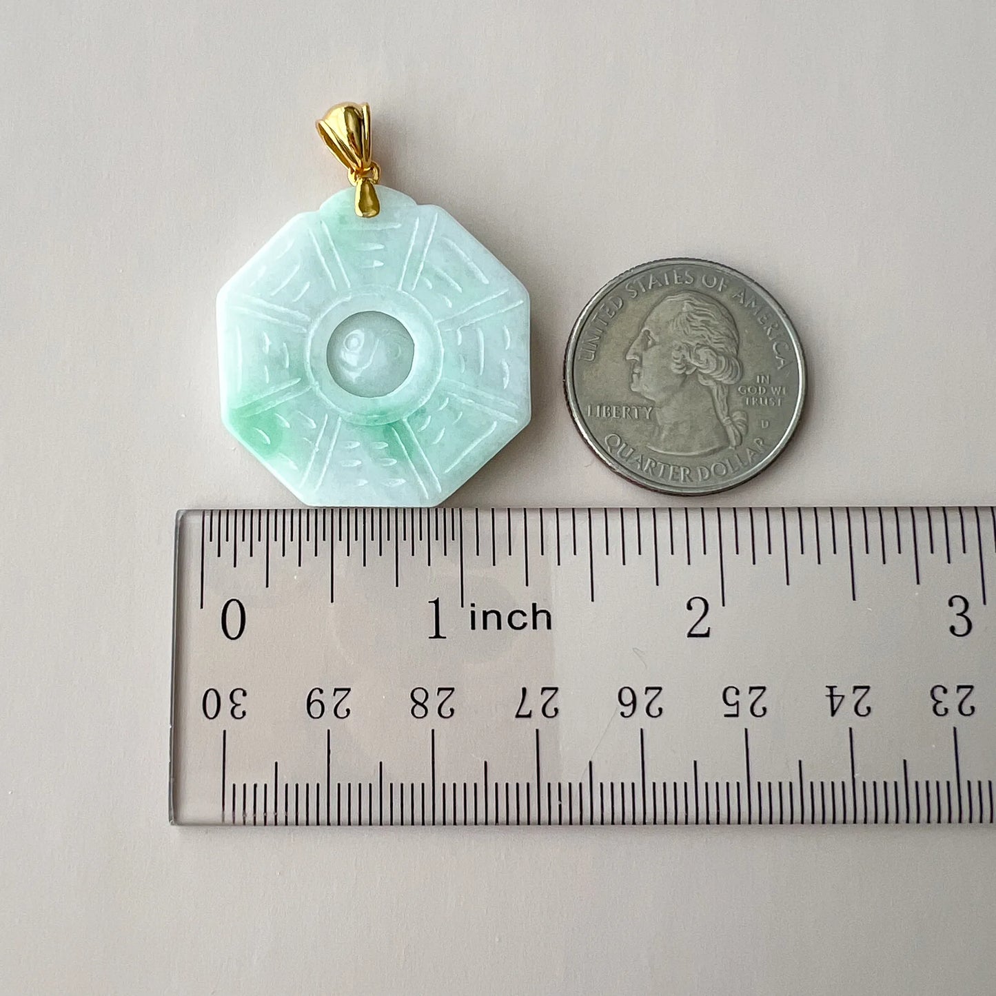 Jade pendant shown beside ruler and quarter for size reference
