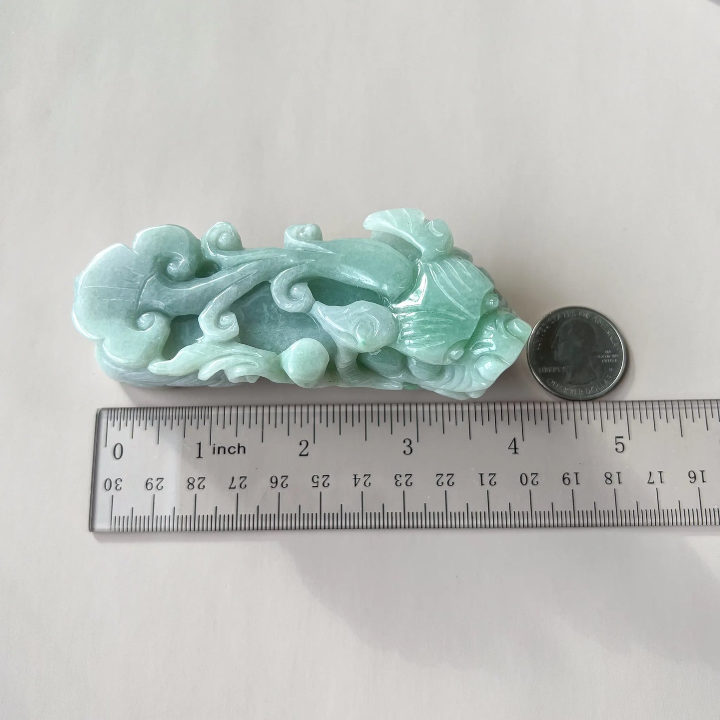 Top view of pale green jade carving shown with ruler and coin for scale