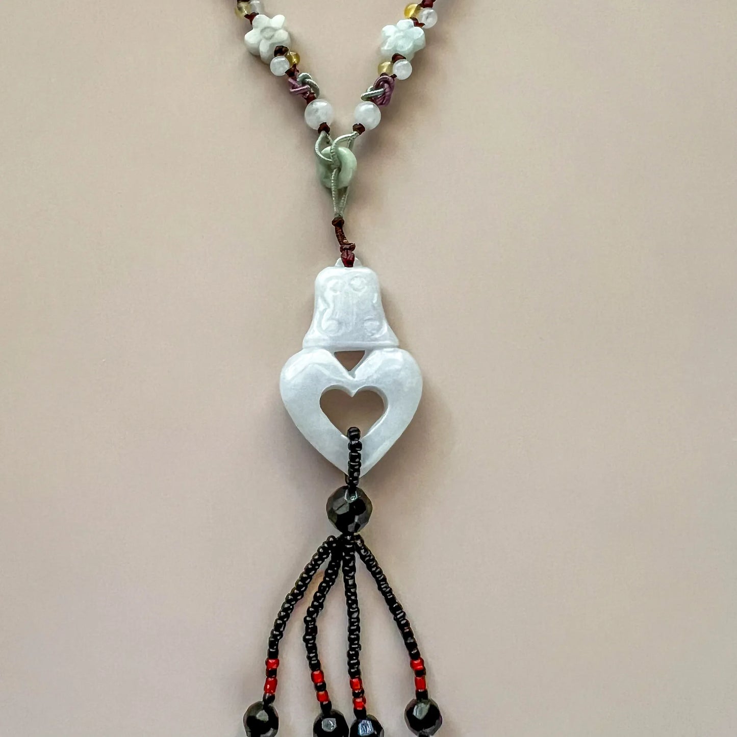Close-up front view of hand-carved white lavender jadeite heart pendant necklace with beaded cord and glossy finish