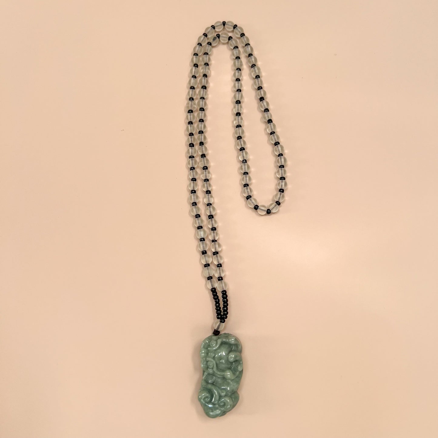 Front view of green jadeite Pixiu pendant necklace with translucent beaded strand and polished carved finish