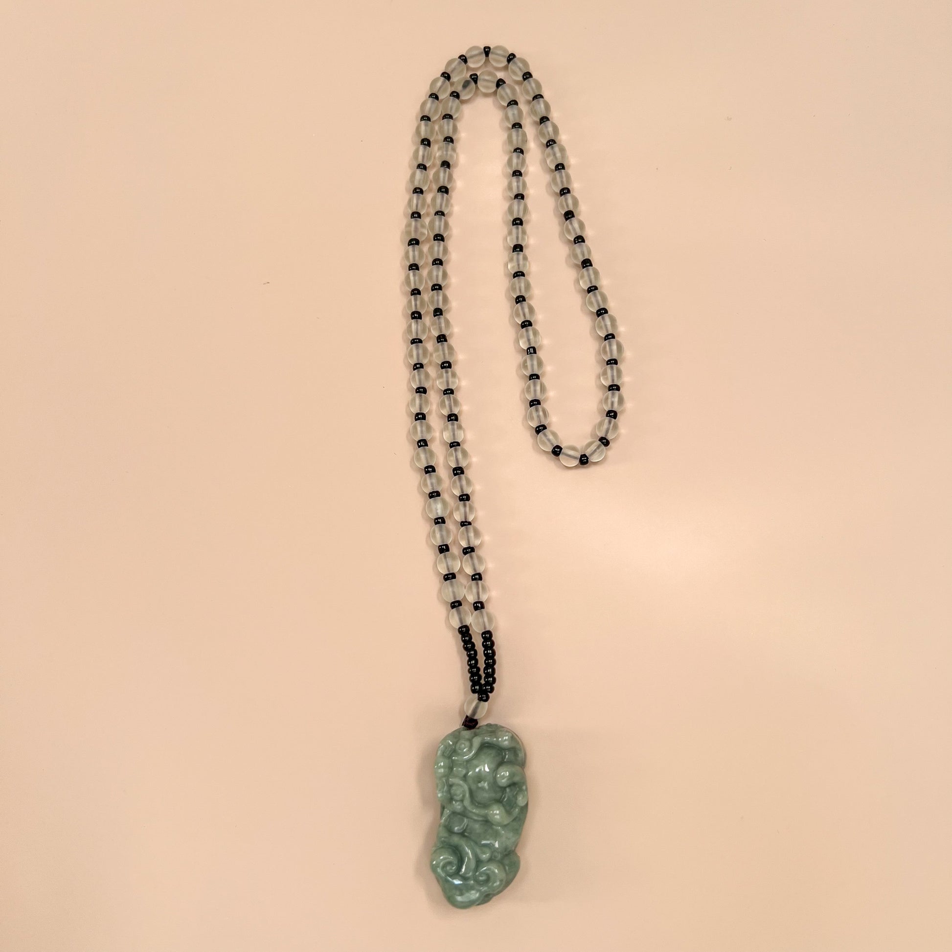 Front view of green jadeite Pixiu pendant necklace with translucent beaded strand and polished carved finish