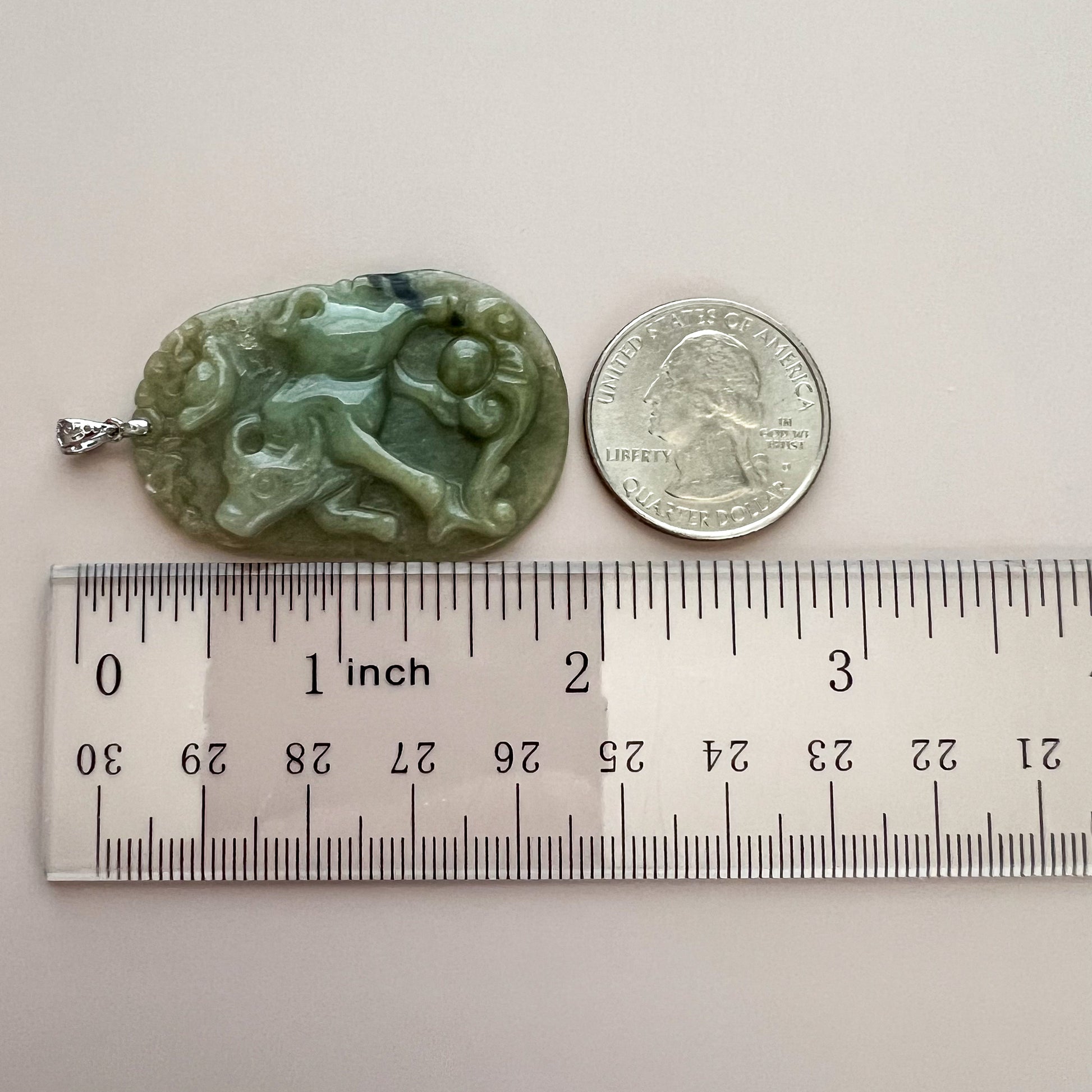 Green jadeite ox with ruyi carving pendant, polished stone texture, sterling silver bail, shown beside quarter and ruler