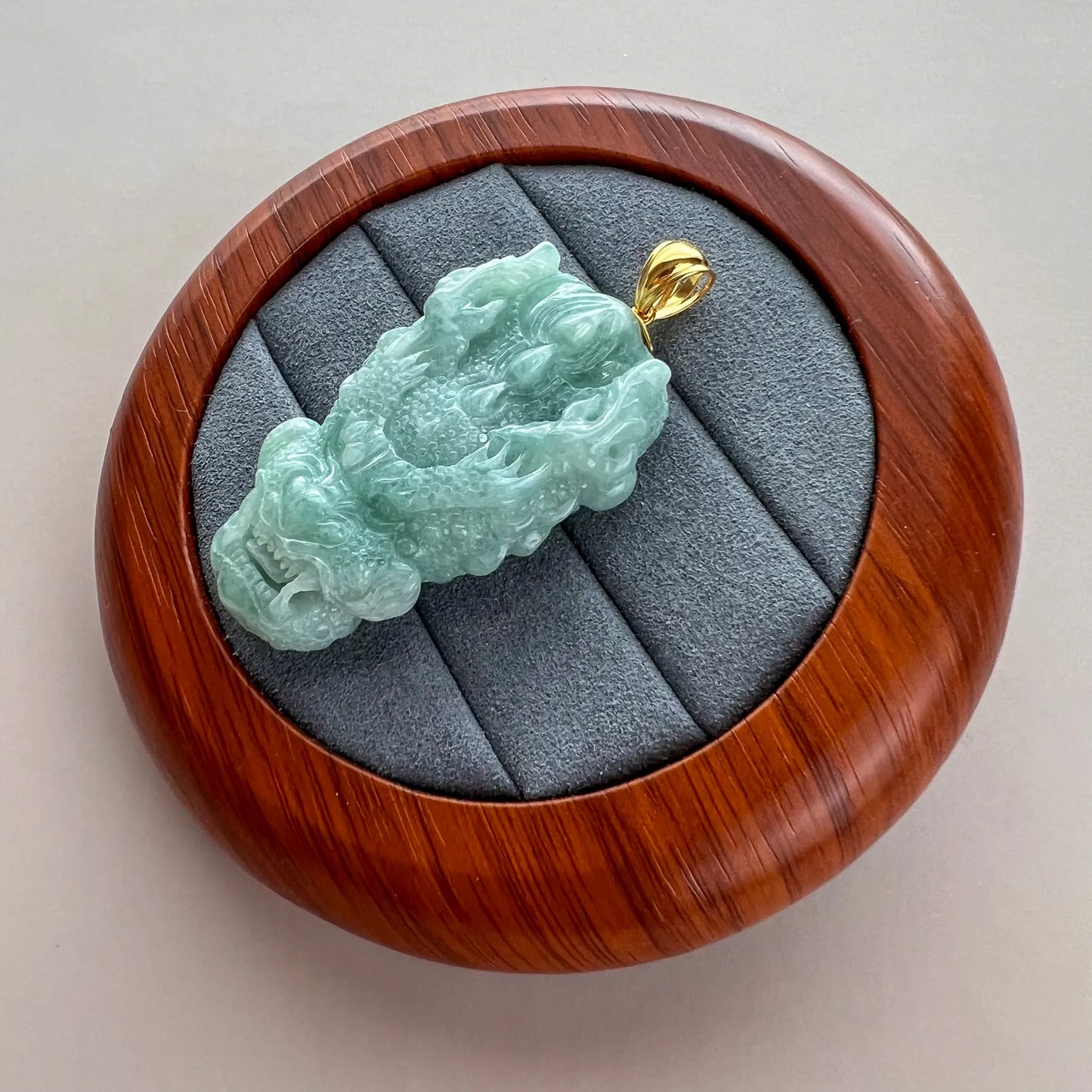Side-angled view of translucent jade dragon pendant showing relief carving and polished finish