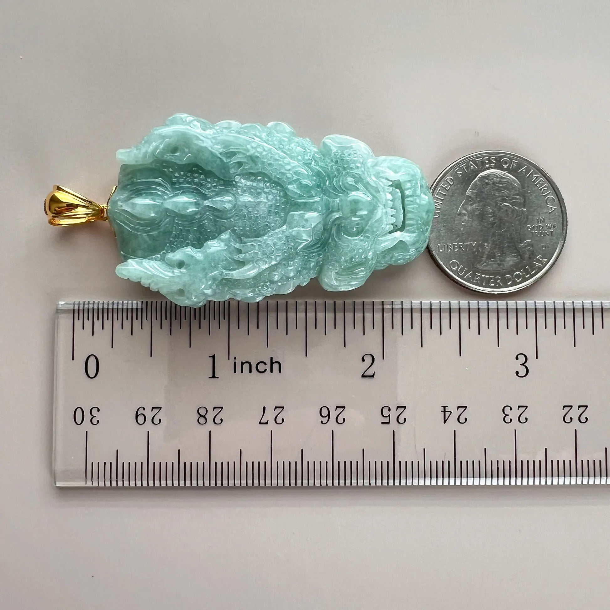 Pendant size reference with ruler and quarter beside green carved jade dragon and gold bail