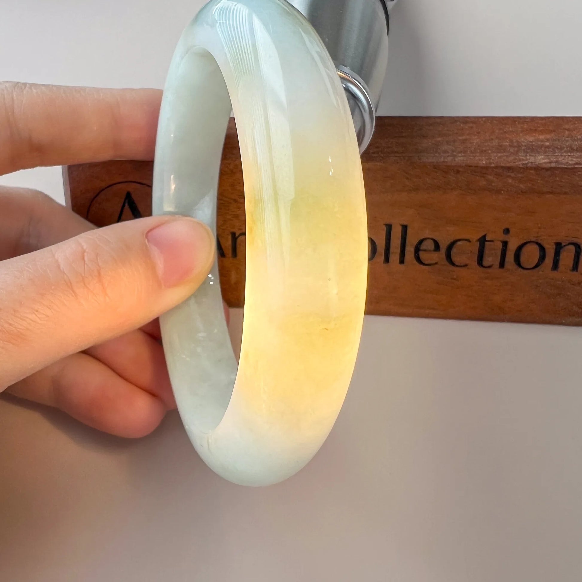 Close side view of translucent jade bangle with yellow and green color grading