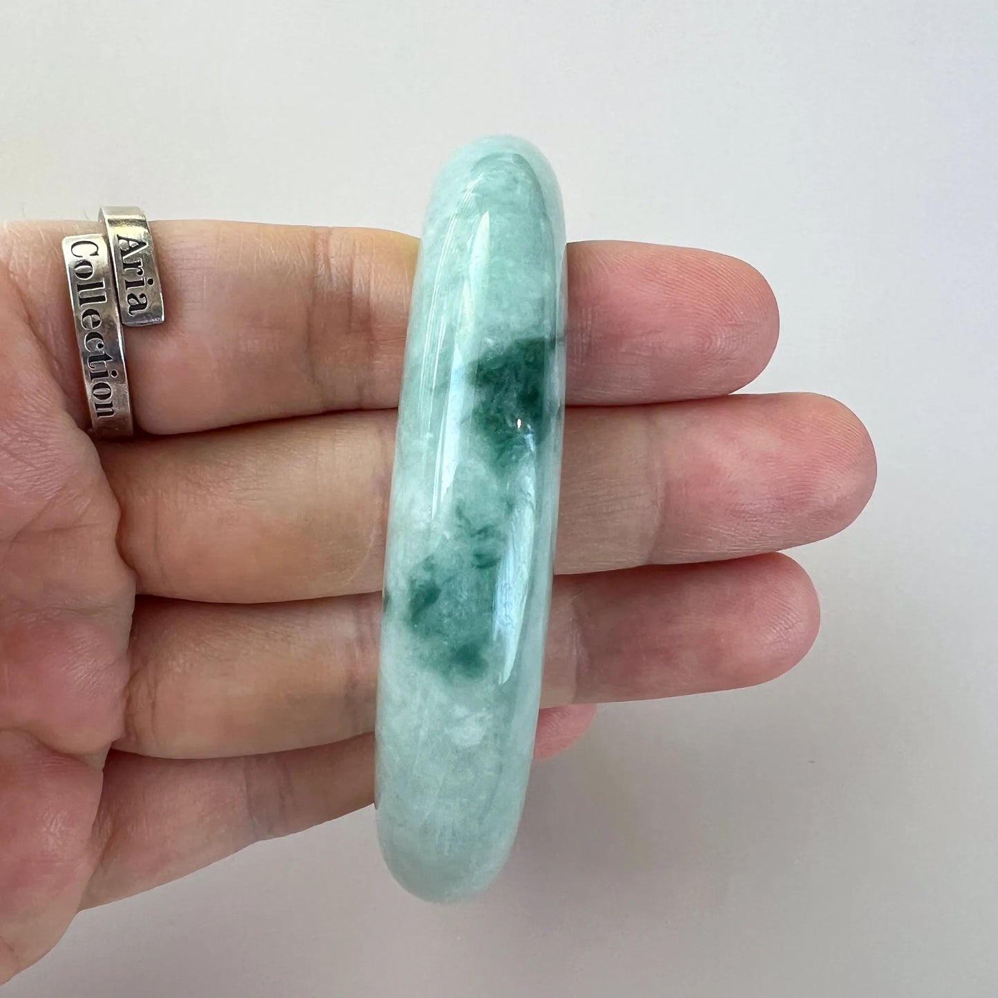 Side view of glossy jade bangle showing thicker profile and dark green marbling