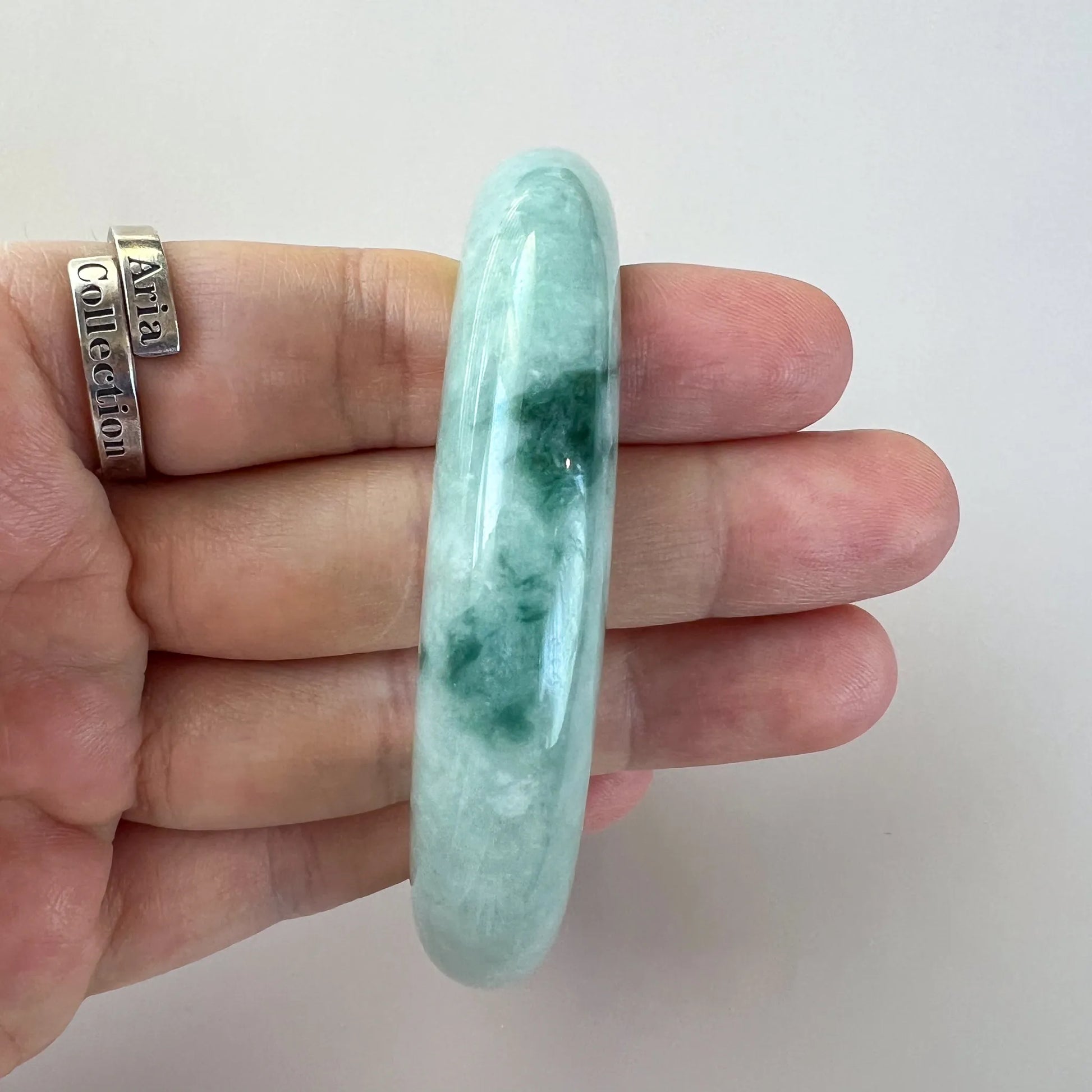 Side view of glossy jade bangle showing thicker profile and dark green marbling