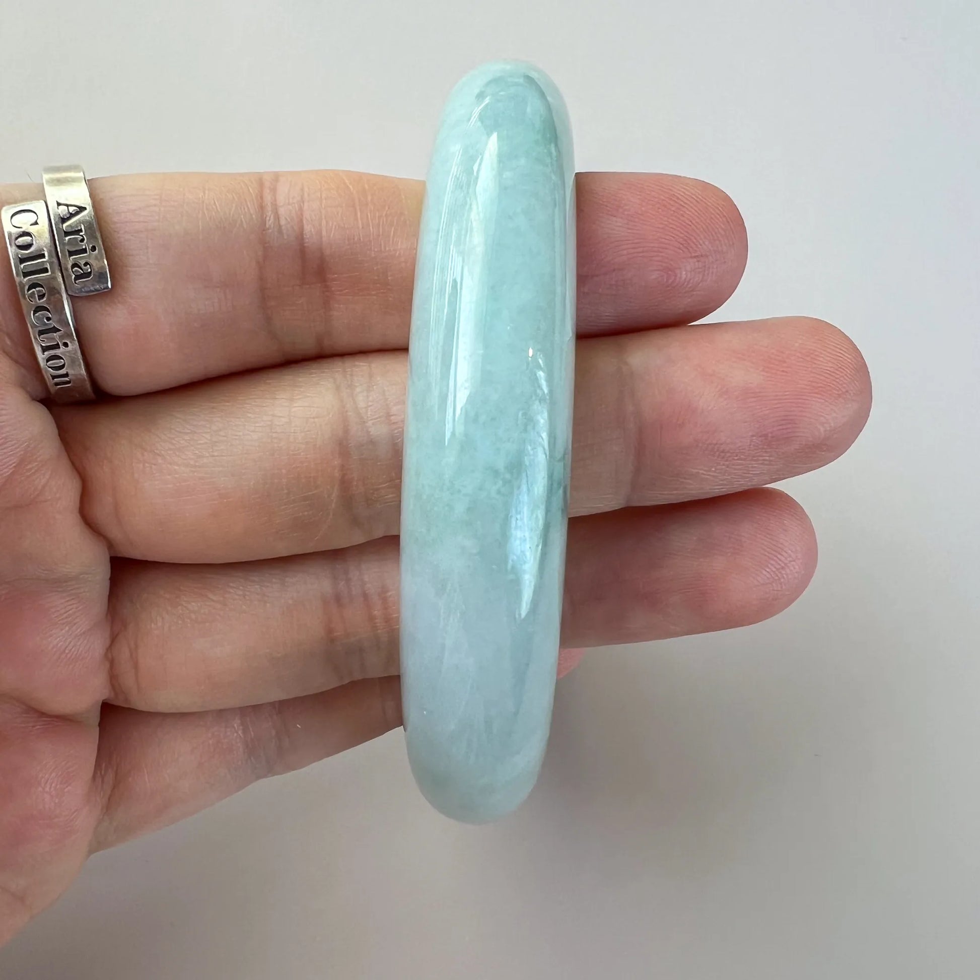 Side view of smooth pale jade bangle with polished finish and subtle clouding