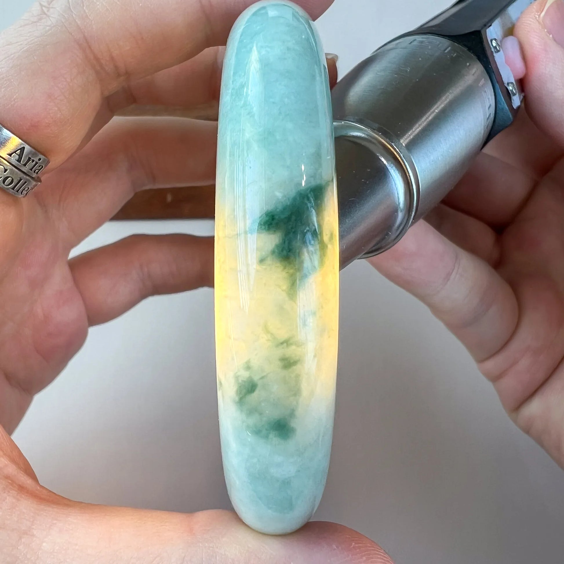 Side view of translucent jade bangle shown against a flashlight to reveal color zoning