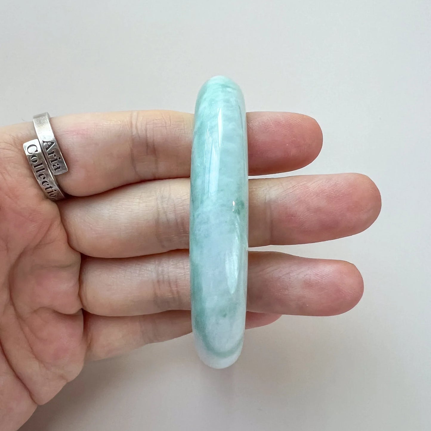 Side profile of polished jade bangle showing thick rounded band and translucency