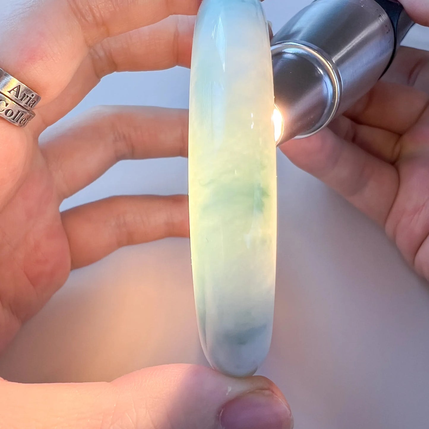 Jade bangle backlit with flashlight, revealing milky translucence and green color
