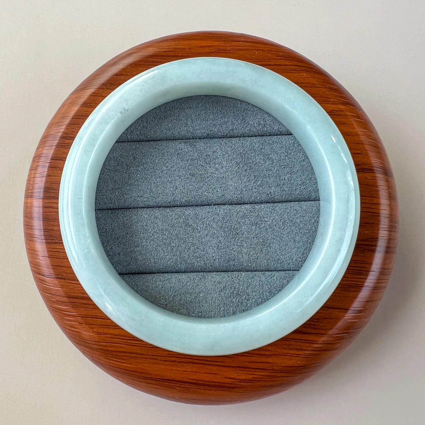 Top view of smooth pale blue jade bangle in a round wood presentation case