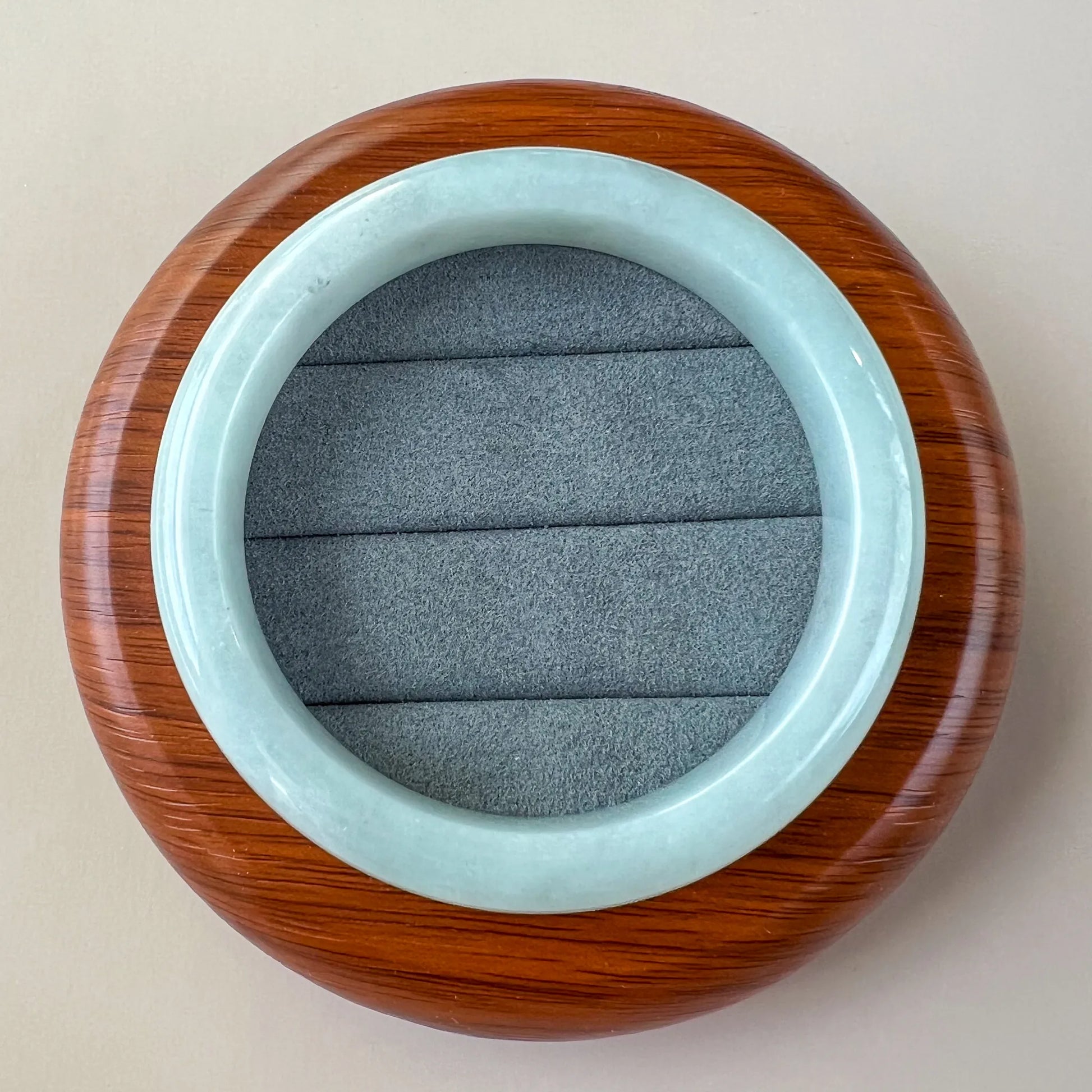 Top view of smooth pale blue jade bangle in a round wood presentation case