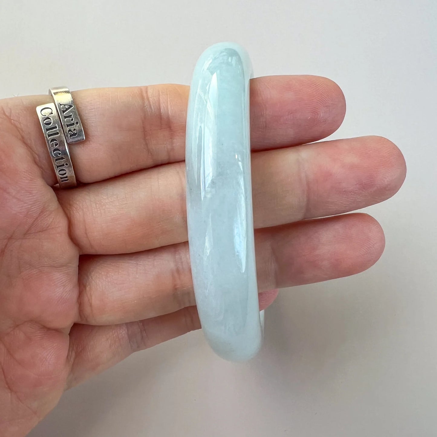 Profile view of smooth light blue jade bangle showing thickness and high-gloss finish