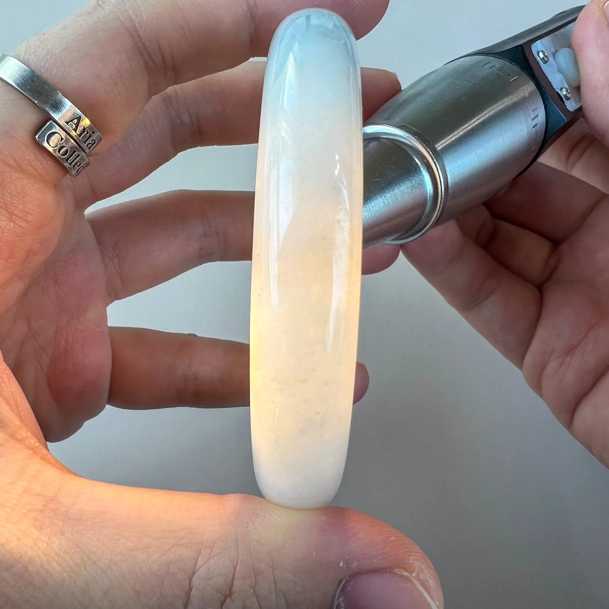Side view of translucent pale jade bangle illuminated to reveal internal color variation