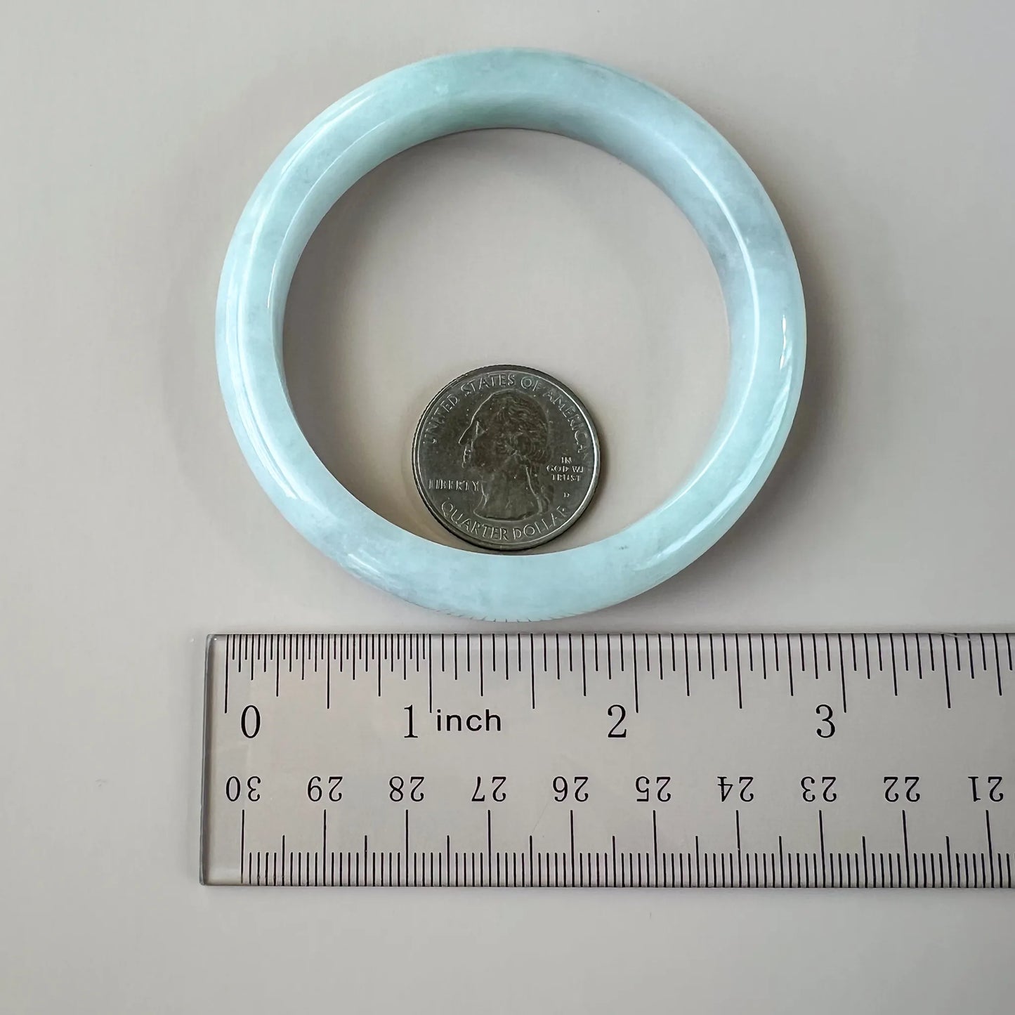 Light blue Natural Jade bangle shown with ruler and quarter for size reference