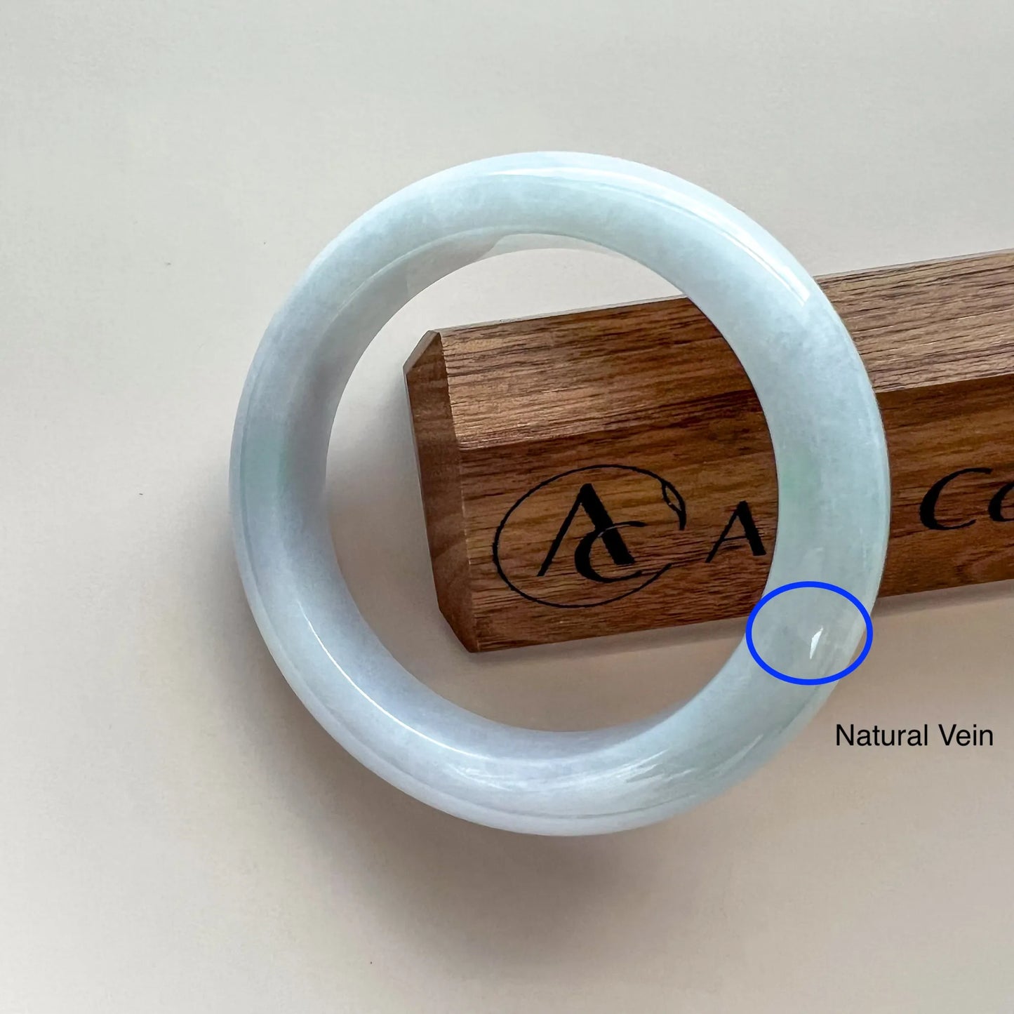 Front view of pale blue polished bangle with natural vein detail on display stand