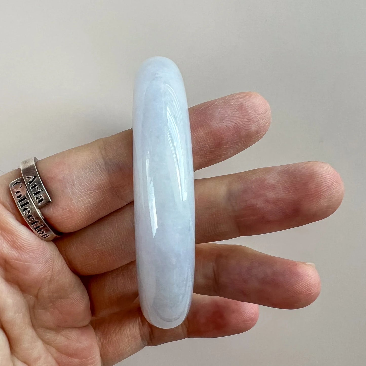 Side profile of polished pale blue jade bangle showing thick rounded band shape