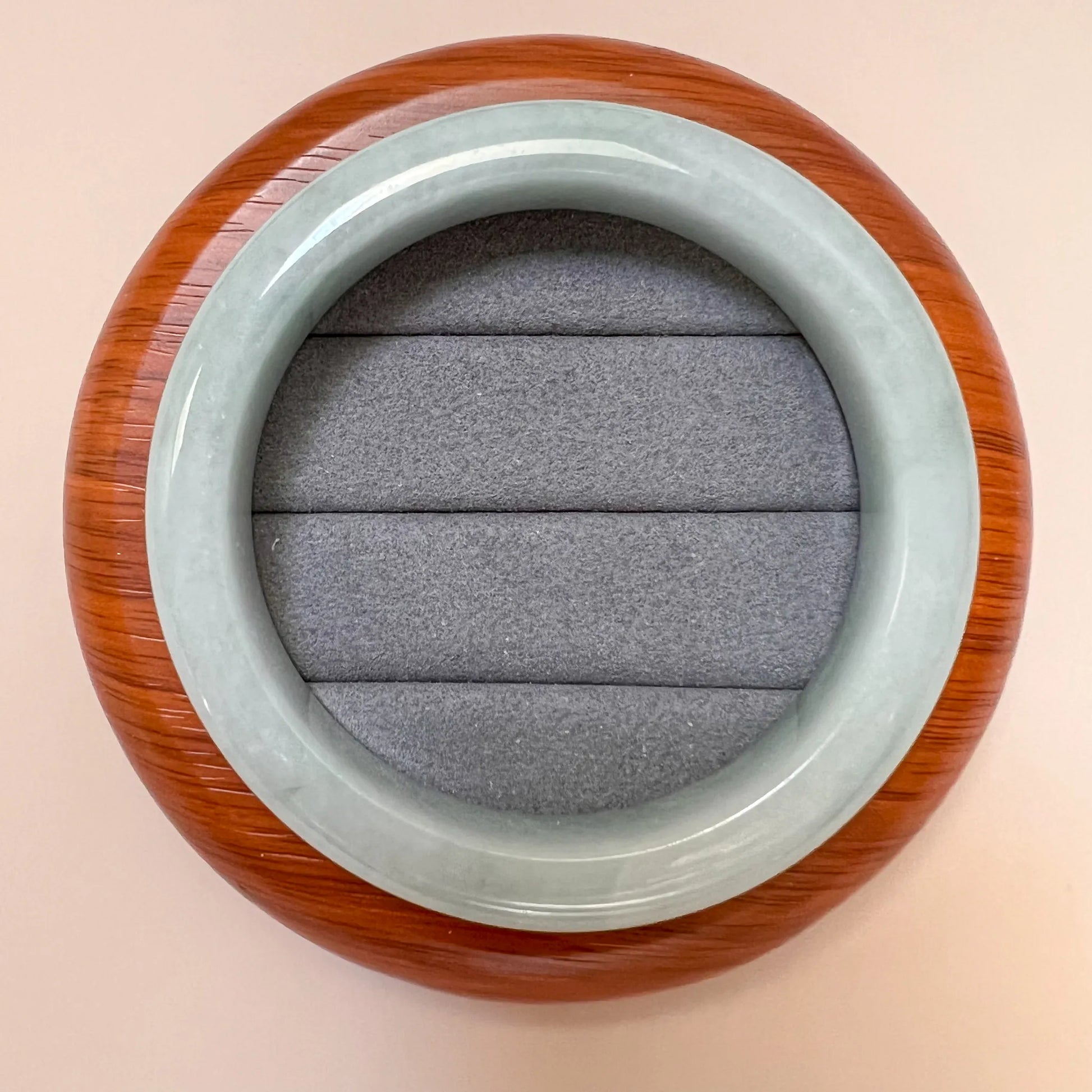 Top-down view of polished jade bangle on round wooden display base