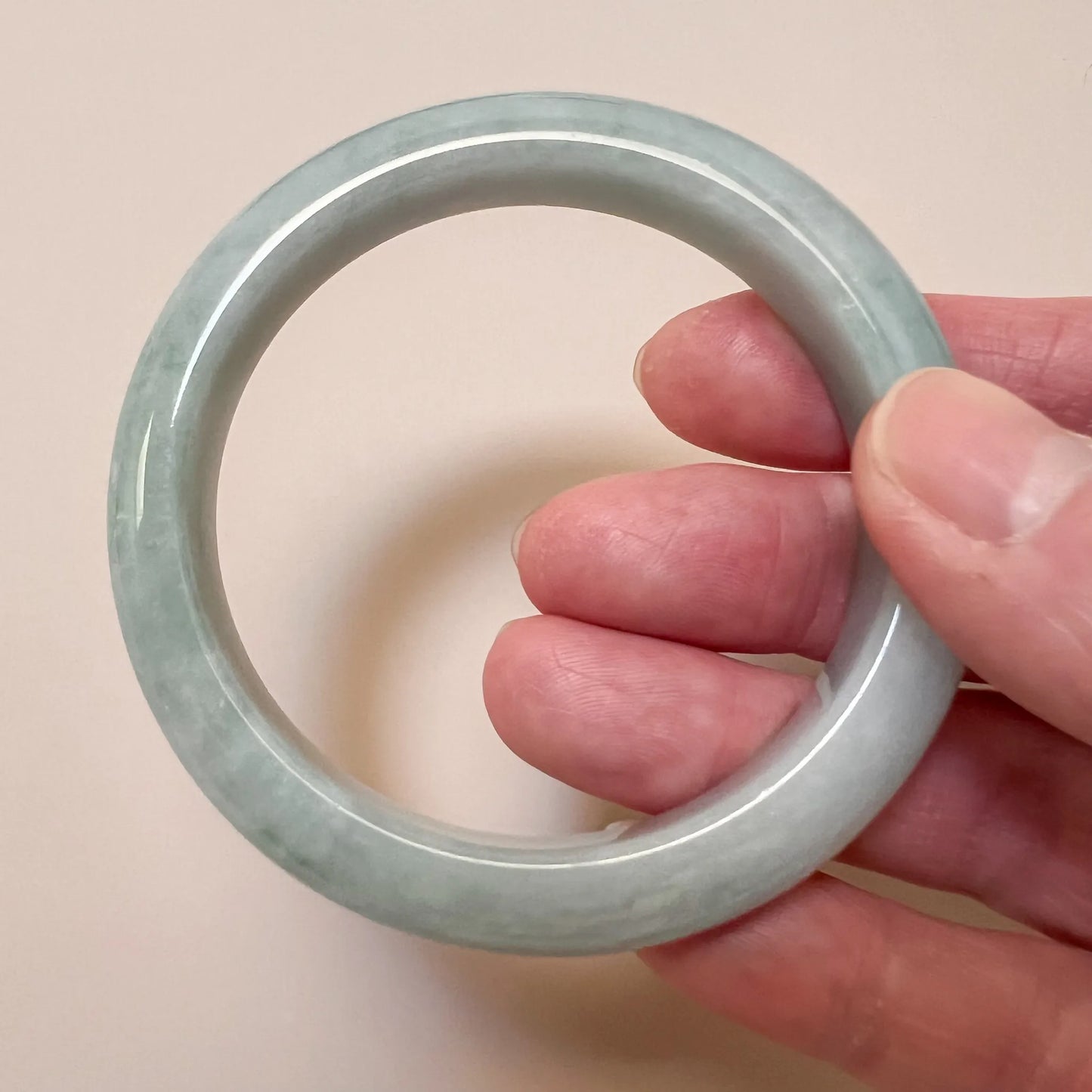 Handheld view of translucent jade bangle with smooth rounded profile