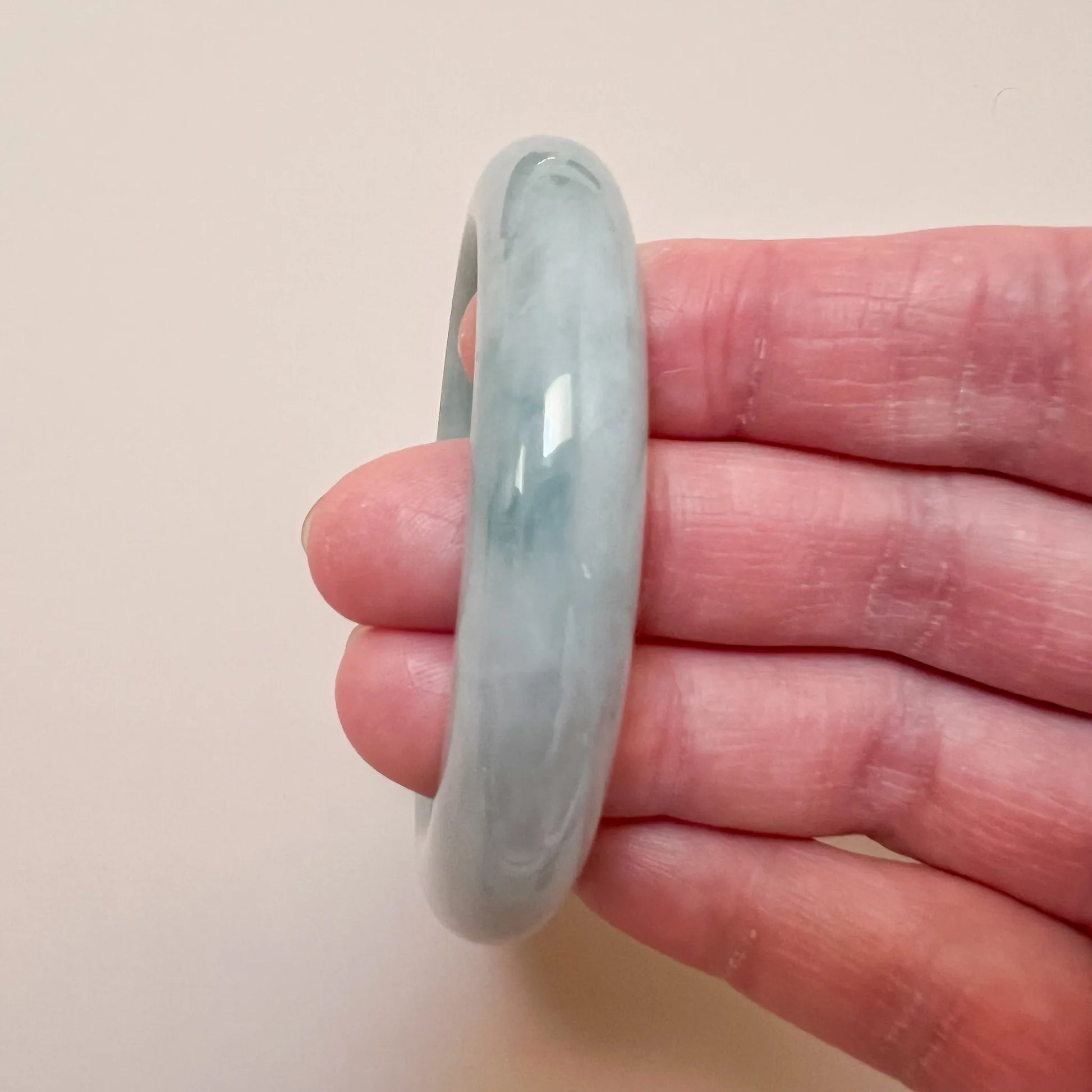 Side profile of the light blue jadeite bangle showing its rounded shape and glossy surface