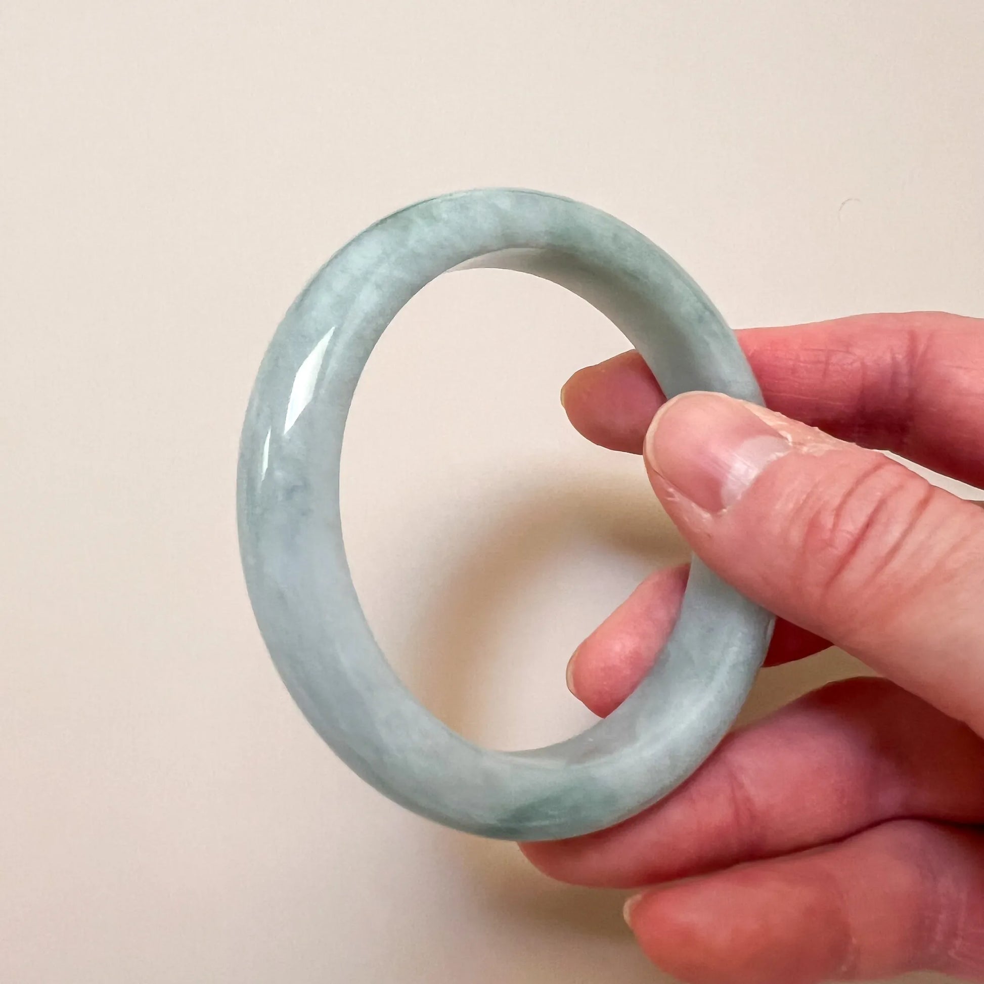 Handheld view of light green jade bangle showing even polished finish
