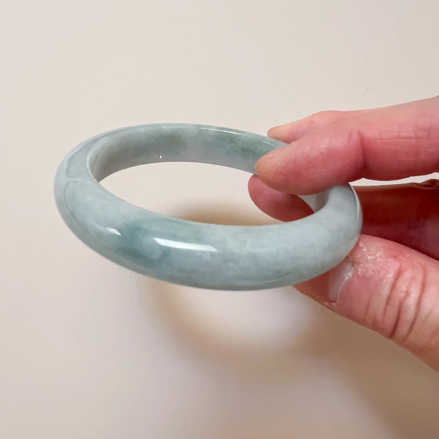 Low angled view of smooth jade bangle with glossy surface and pale marbling