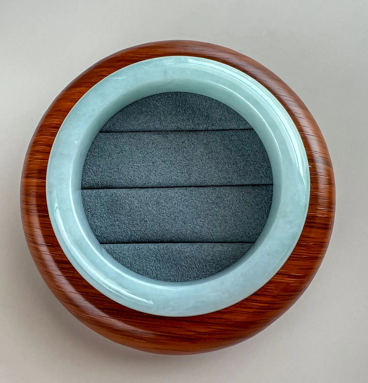Top view of smooth light blue jade bangle on a round wooden stand with gray insert