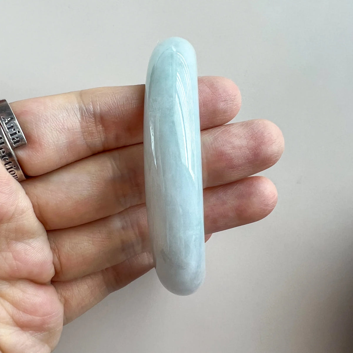 Side profile of smooth pale blue jade bangle showing rounded thickness and glossy finish