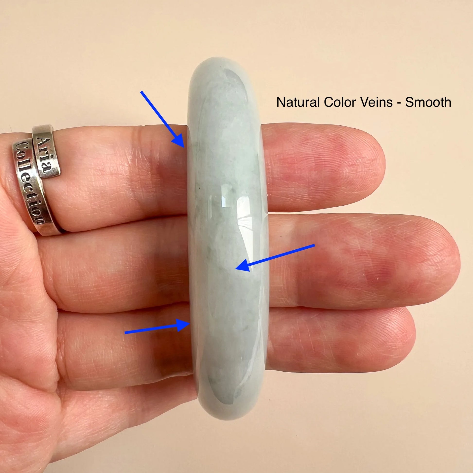 Narrow side view of smooth jade bangle with natural color veining shown in hand