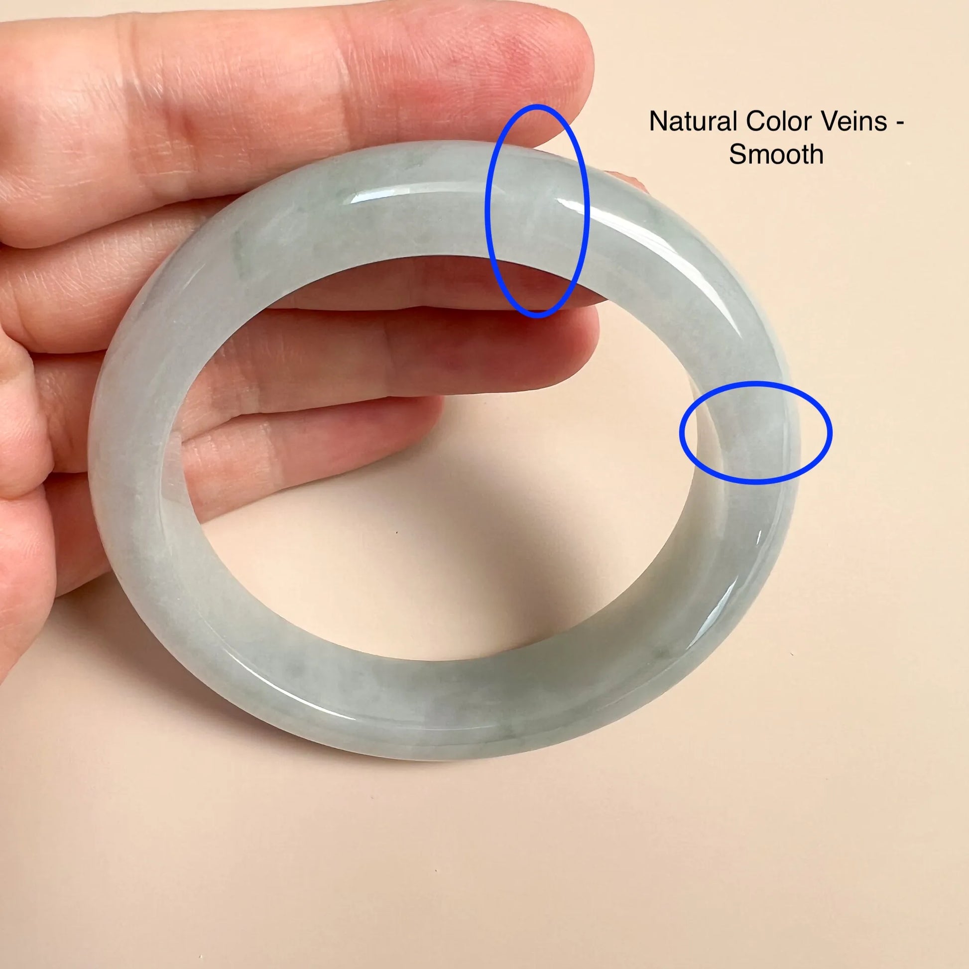 Close-up of jade bangle with natural color veining and glossy polished finish in hand
