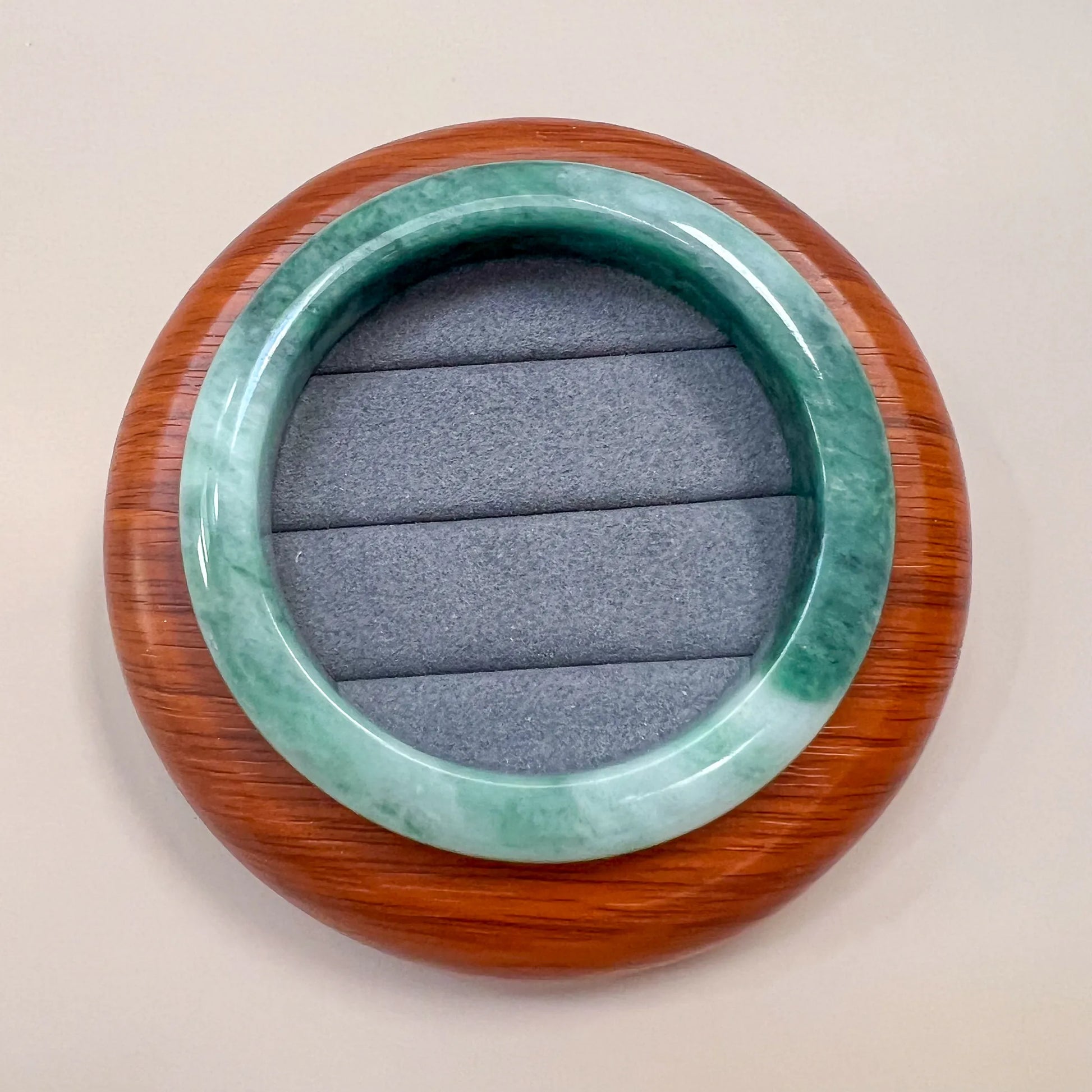 Top view of polished green jade bangle resting on a round wooden display base