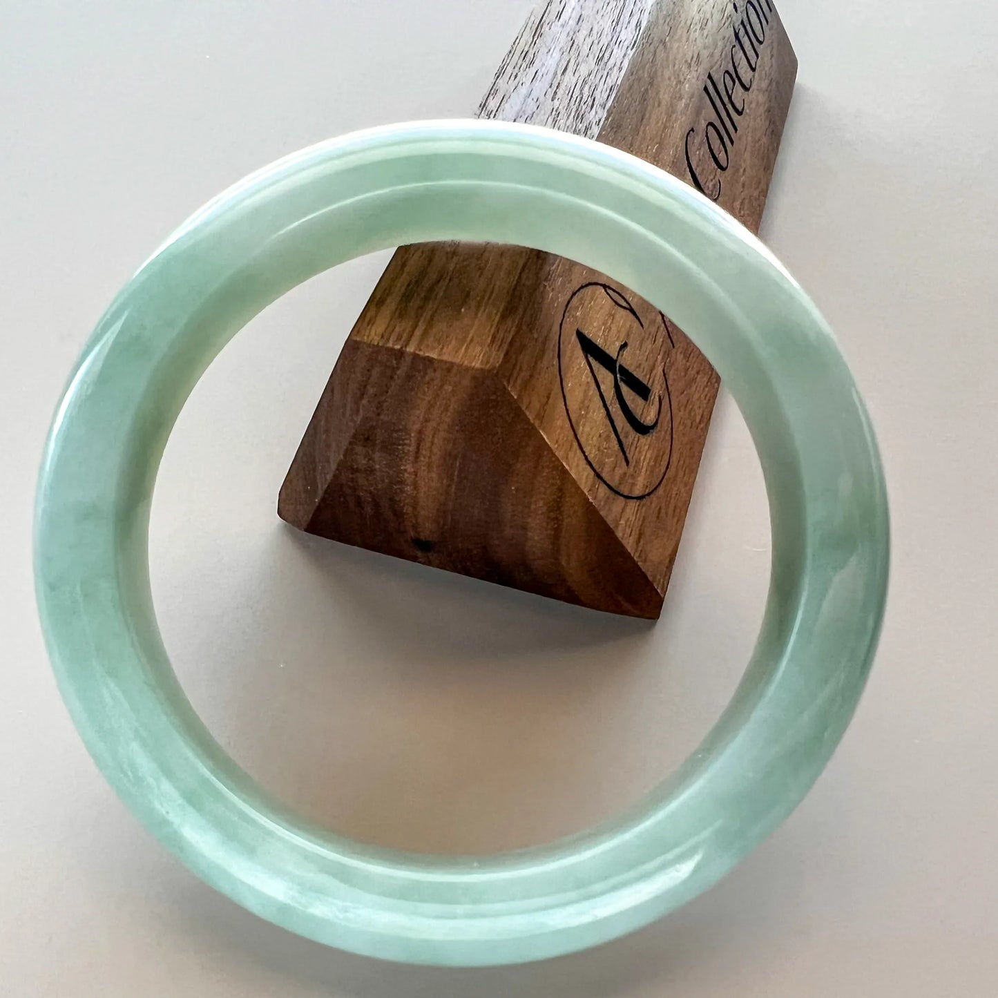 Round jade bangle front view on wooden display stand