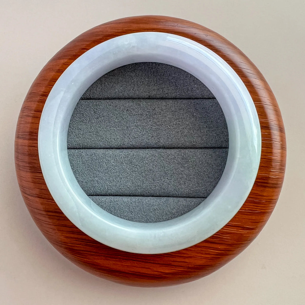 Jade bangle in display box, top view showing smooth polished surface and translucent finish