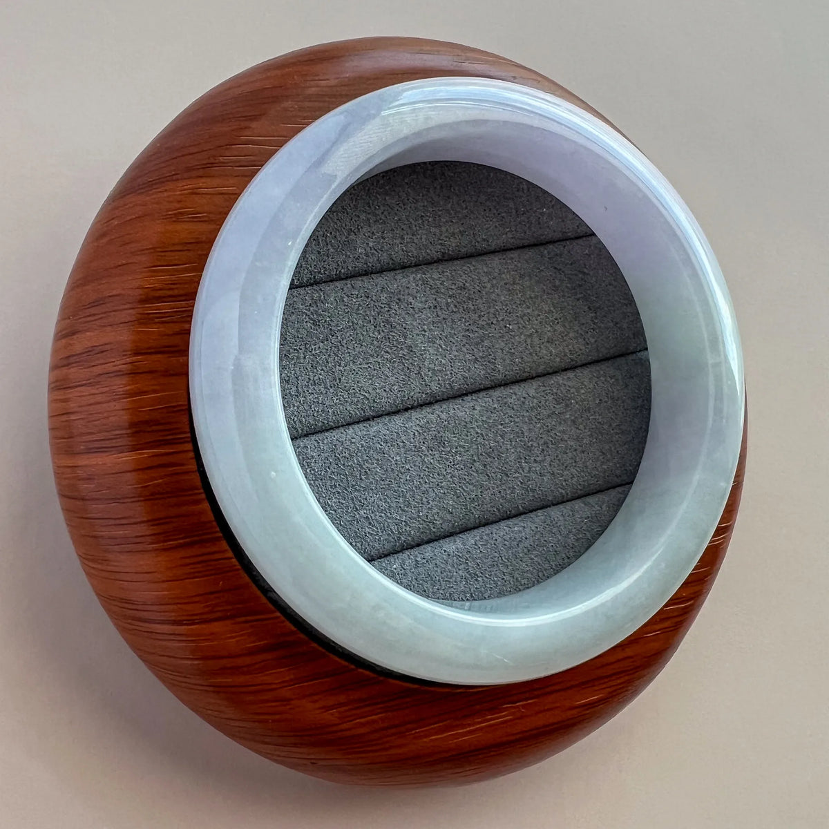 Slightly angled top view of round jade bangle with glossy pale blue finish and wood case