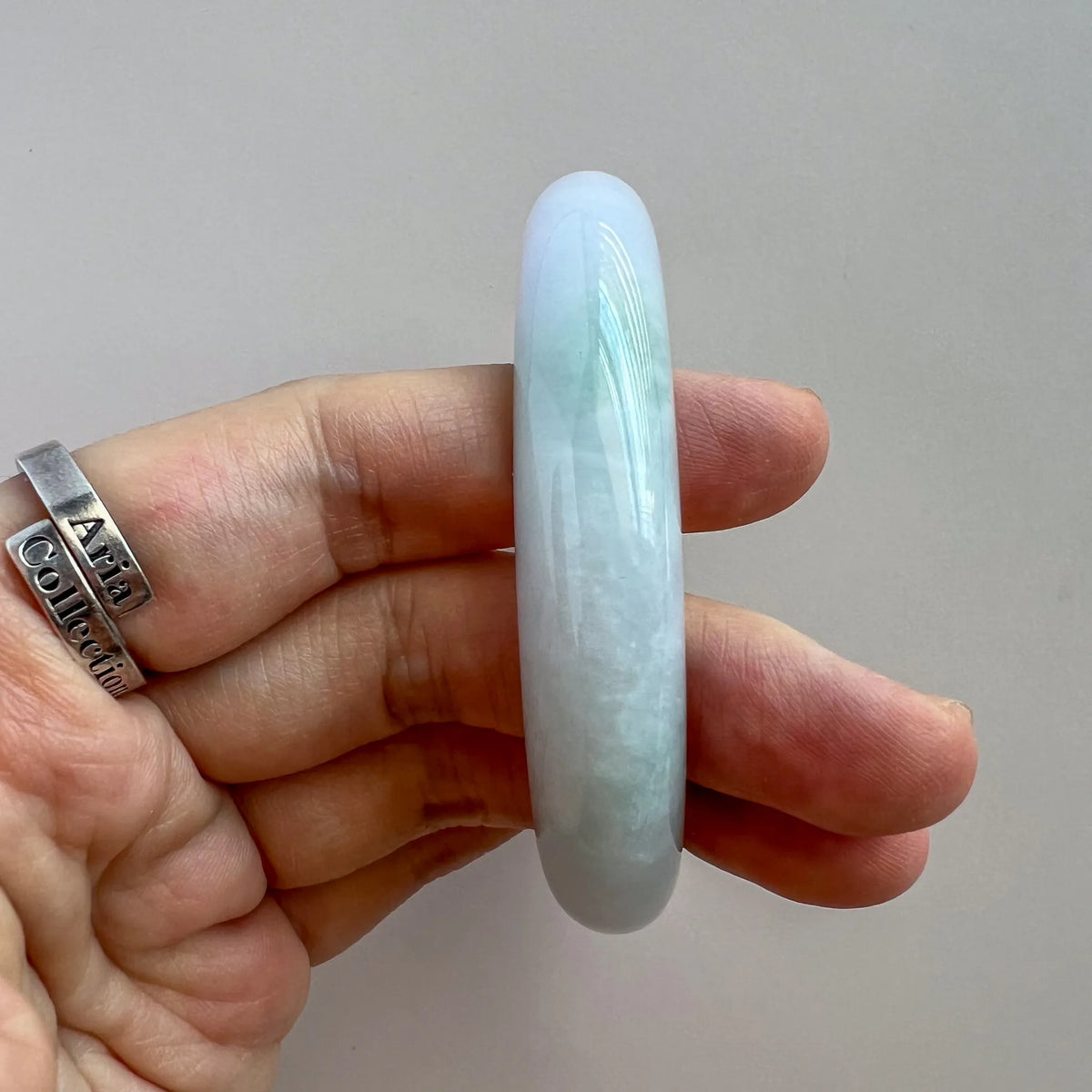 Side profile of pale blue jade bangle showing thick rounded band and polished sheen