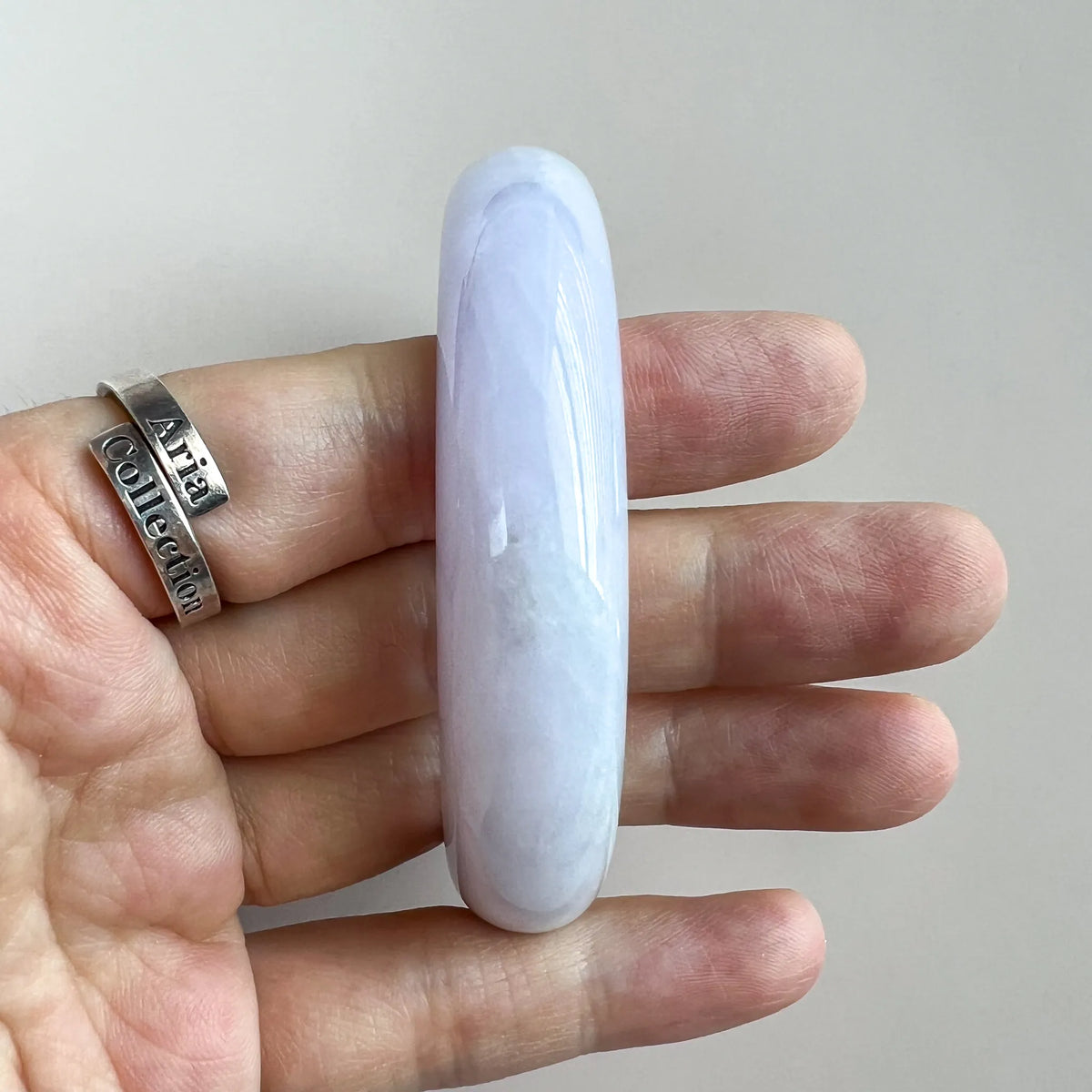 Side profile of smooth pale lavender jade bangle shown on hand for scale