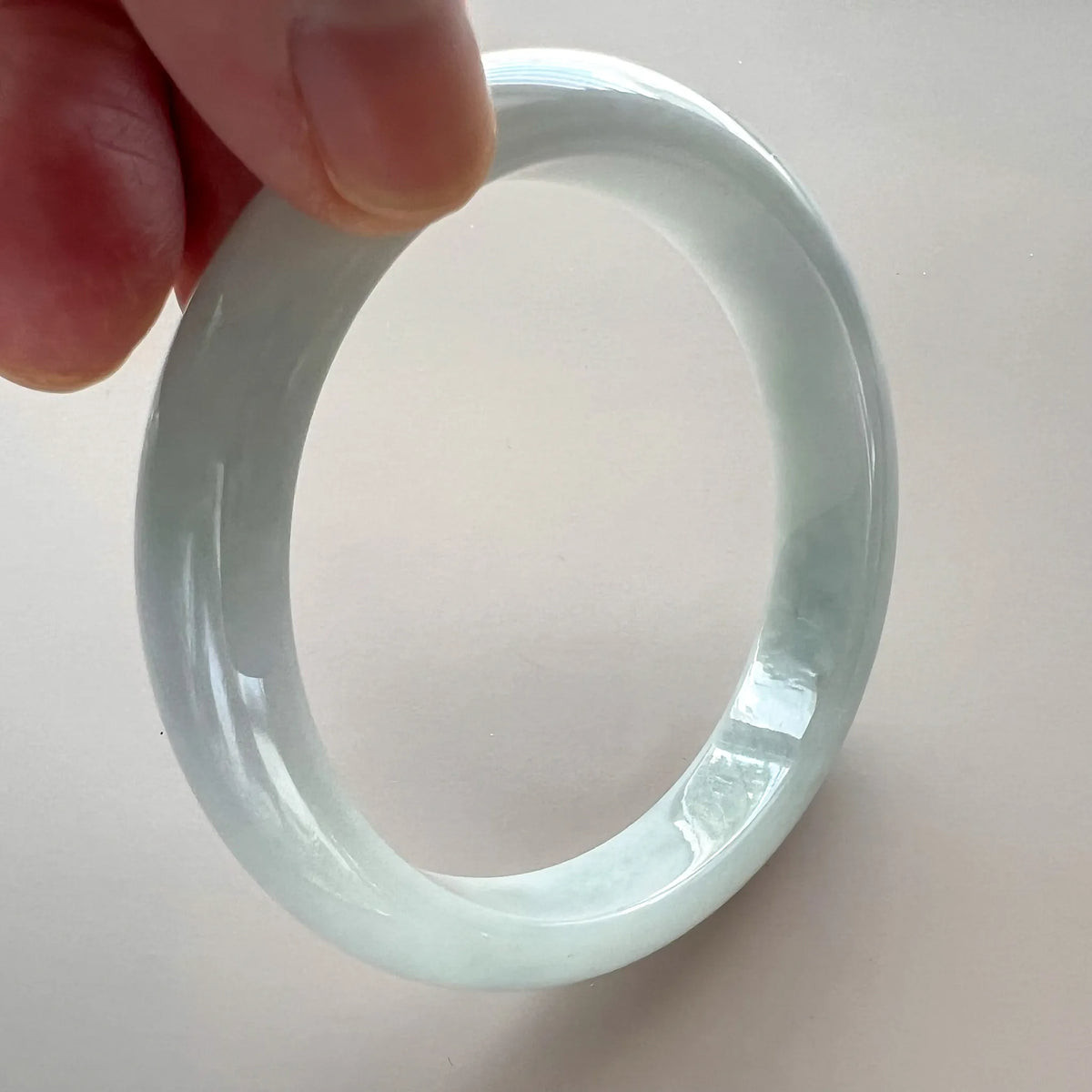 Side view of the translucent jadeite bangle showing its rounded profile, inner surface, and glossy polish