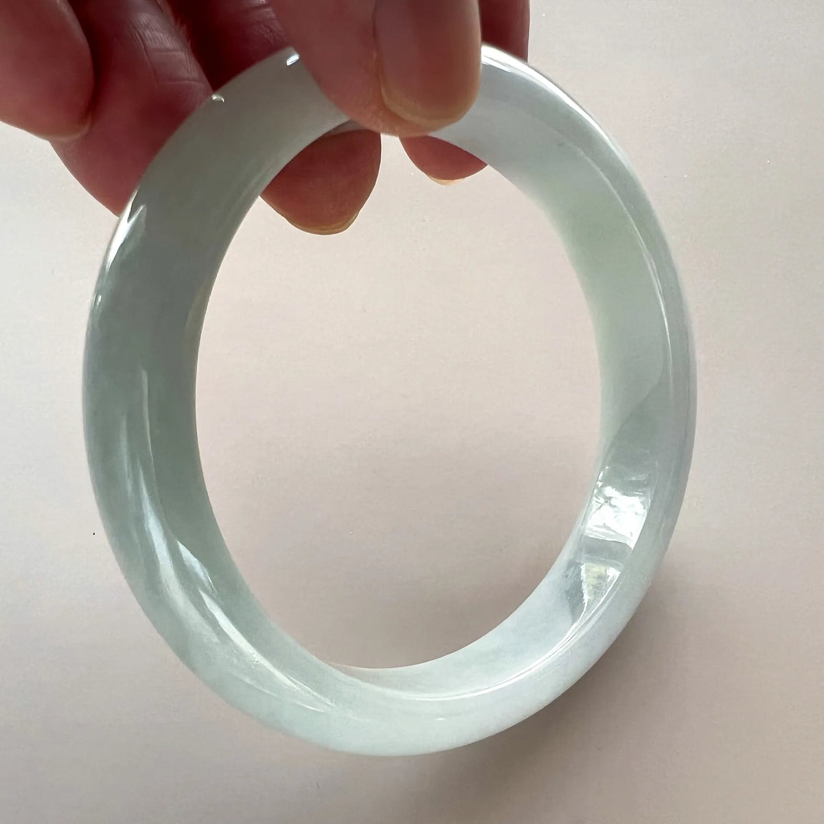 Handheld view of translucent jade bangle with smooth polished finish