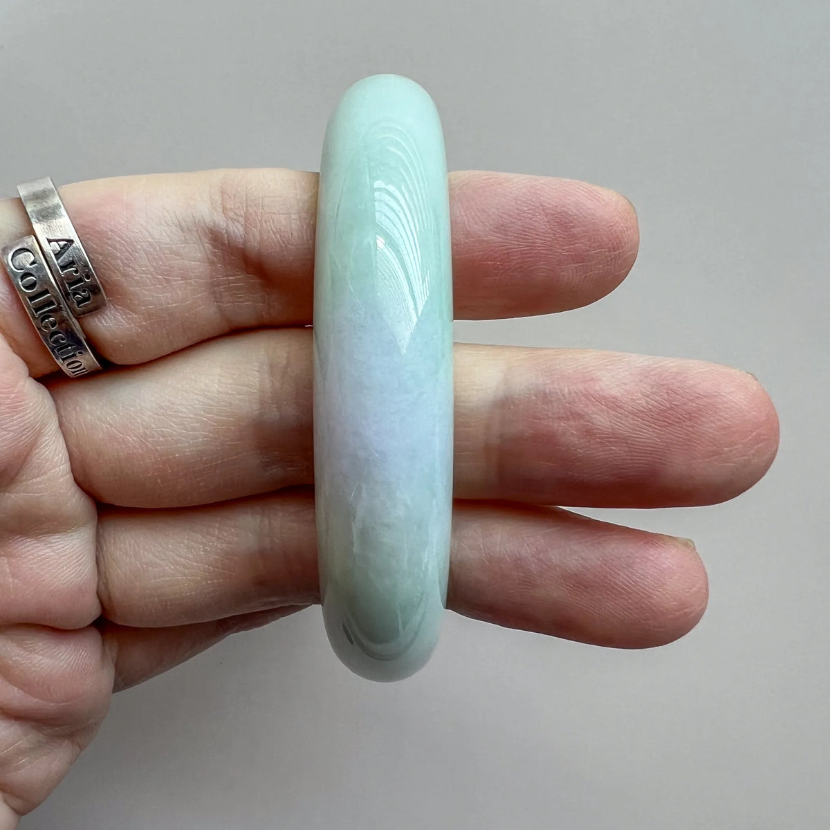 Side view of jade bangle on fingers showing curved profile and high polish