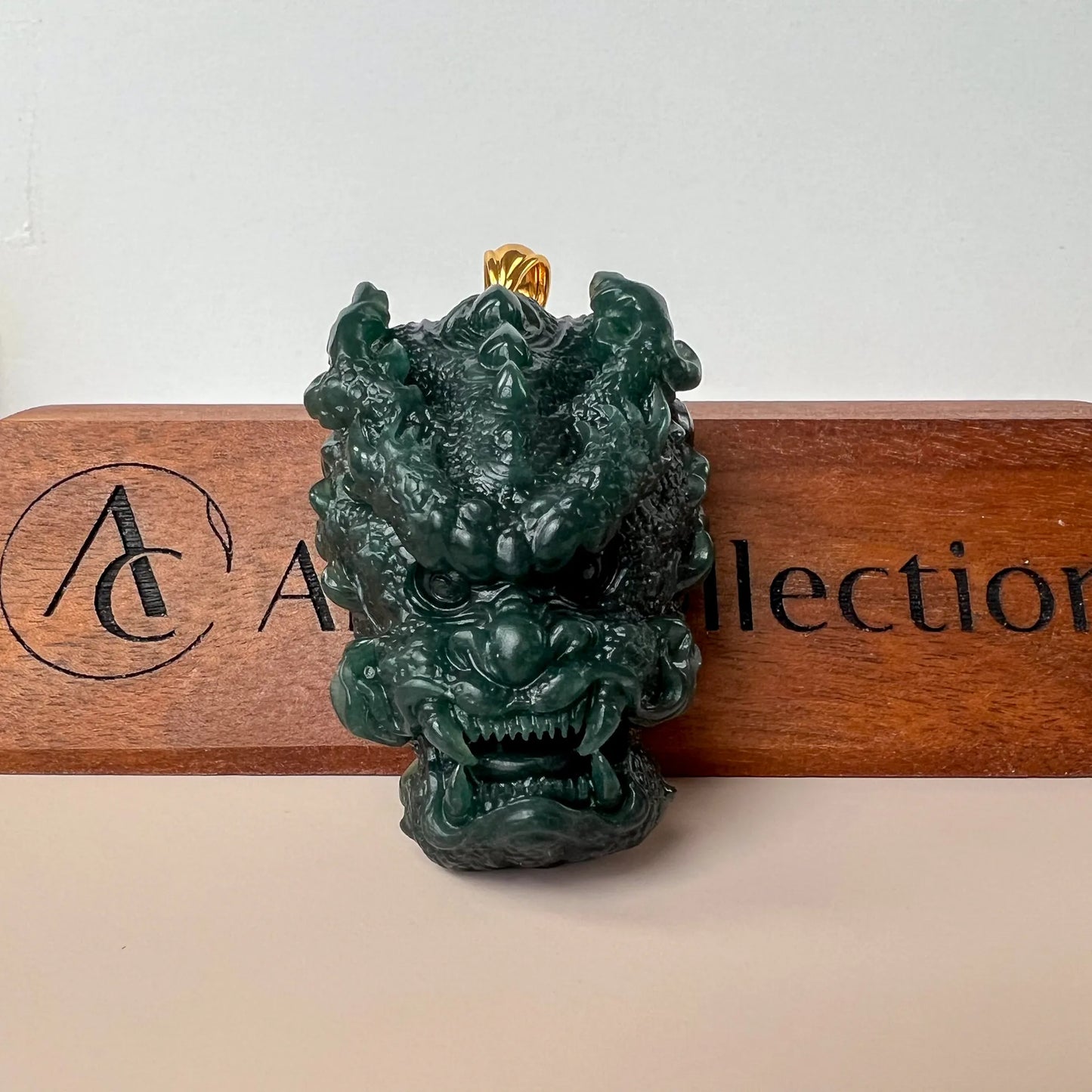 Front view of carved green jade dragon pendant shown on branded wooden stand