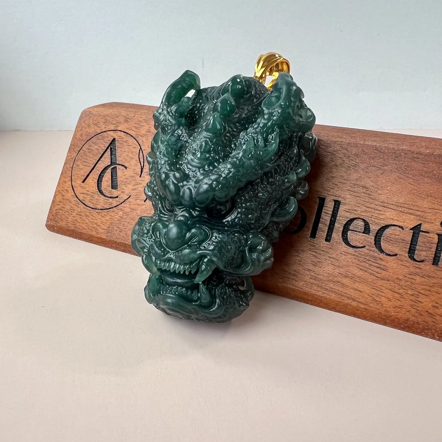 Angled front view of green jade dragon pendant with polished gold bail