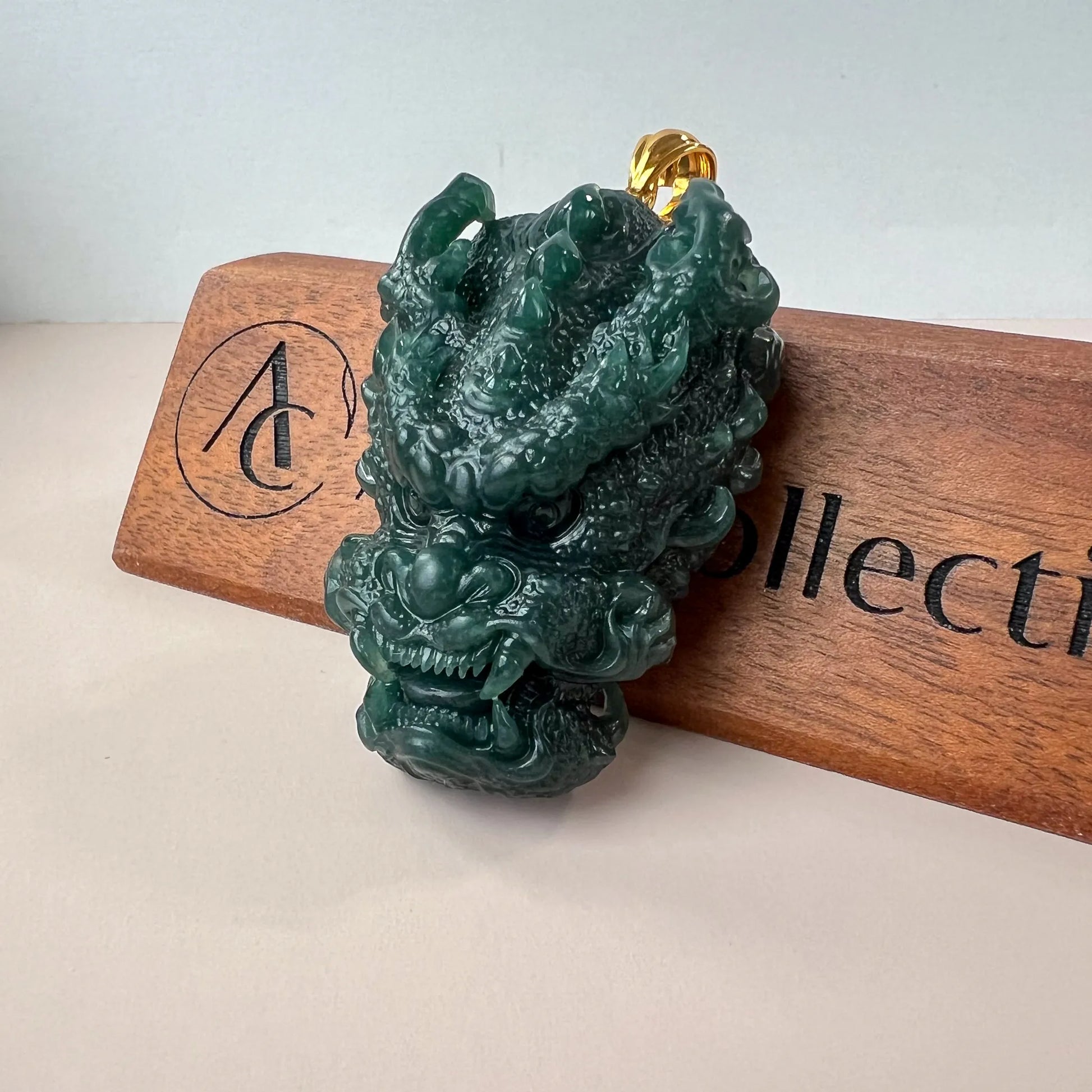 Angled front view of green jade dragon pendant with polished gold bail