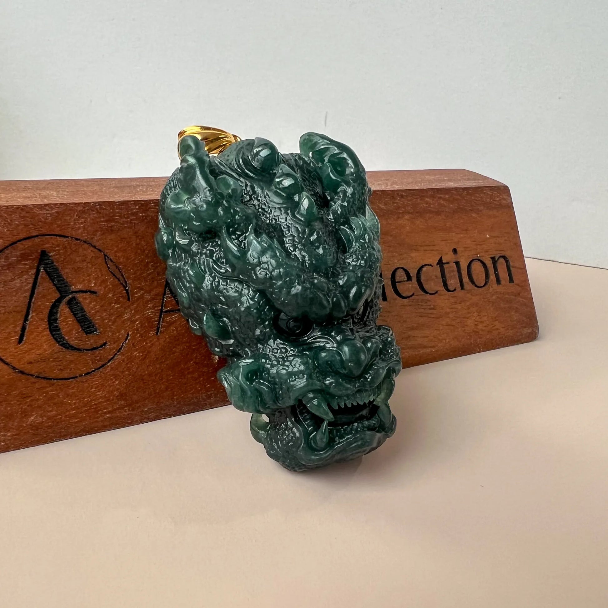 Three-quarter view of carved green jade dragon pendant on wooden display block