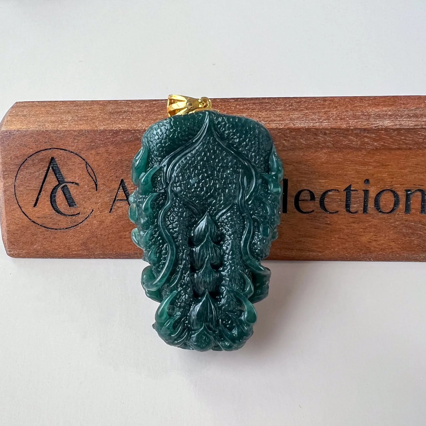 Back view of dark green Natural Jade pendant showing flowing relief carving and gold-tone bail
